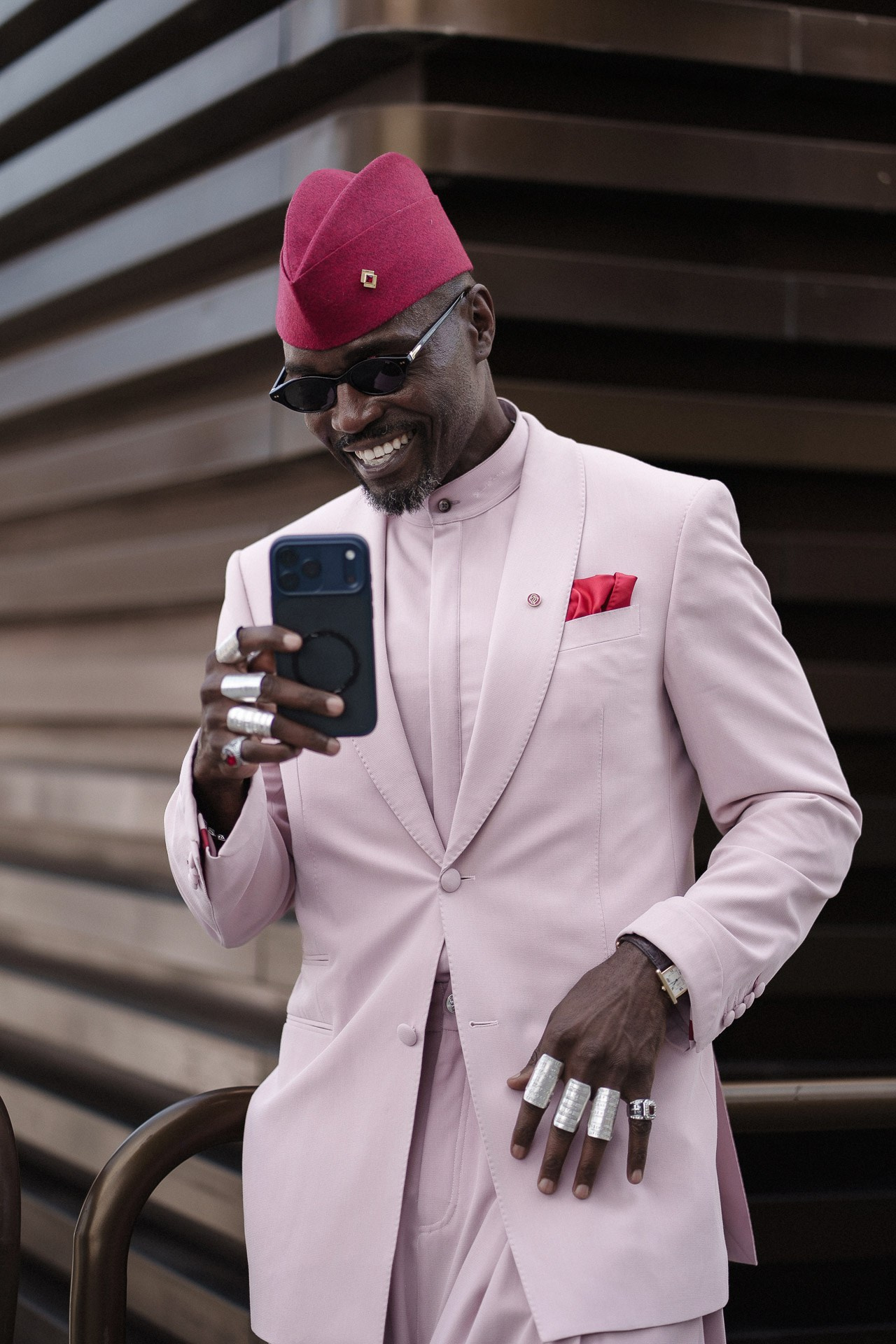 Pitti Uomo 110 street style portrait, guest in pale pink suit and magenta hat using a phone in Florenc