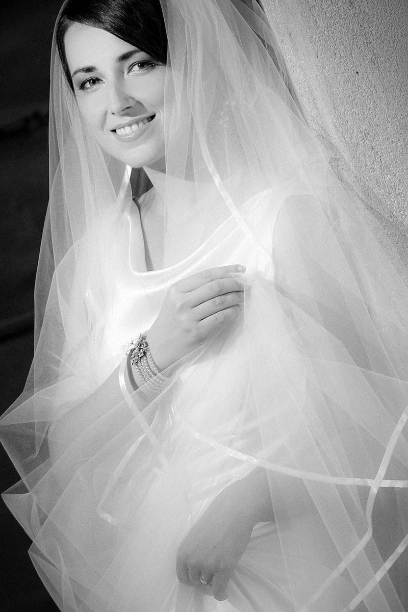 Monochrome of the bride with her veil, gazing into the camera.