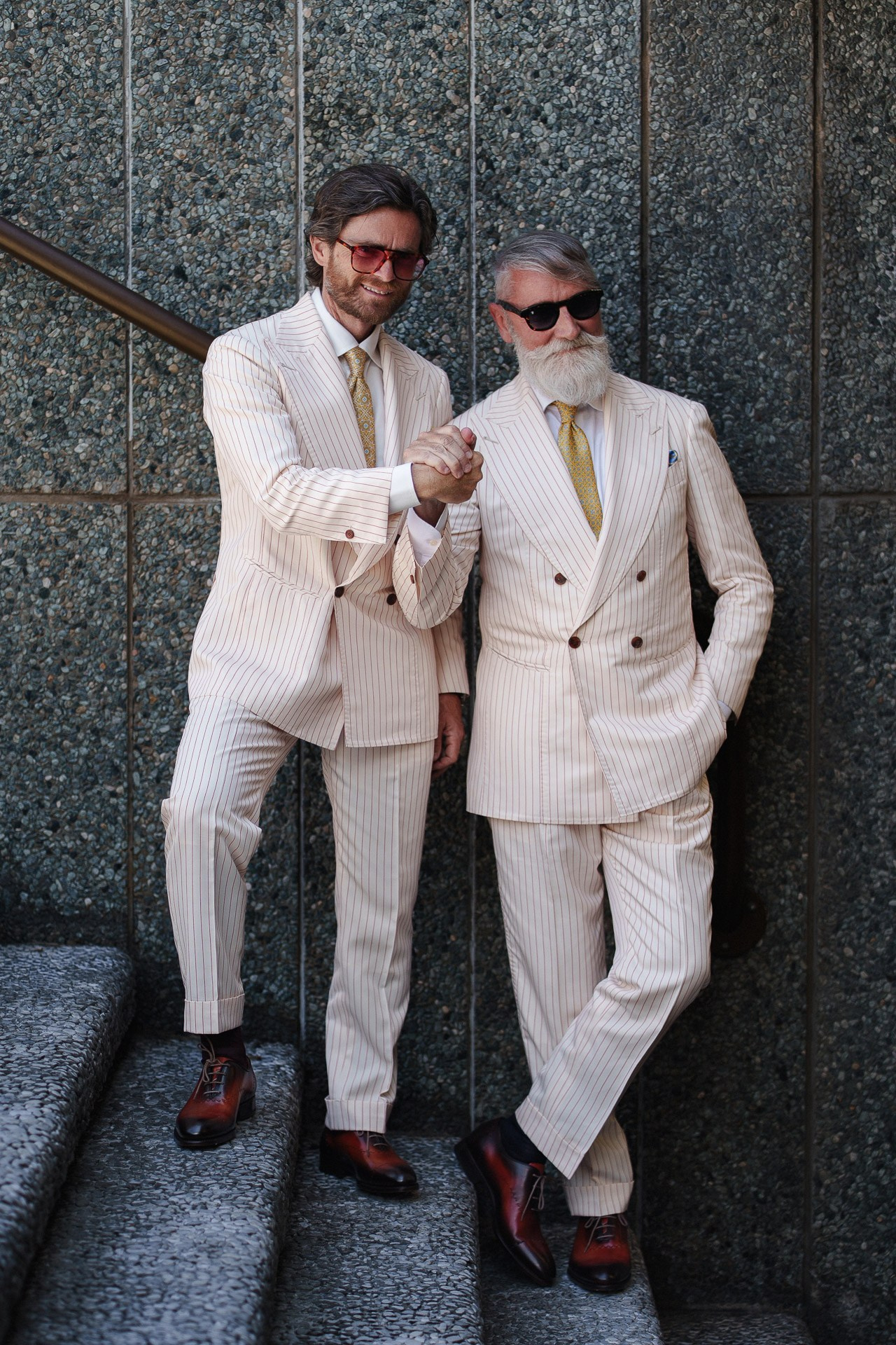 Pitti Uomo 110 street style portrait of two men in cream striped suits outside Fortezza da Basso in Florence