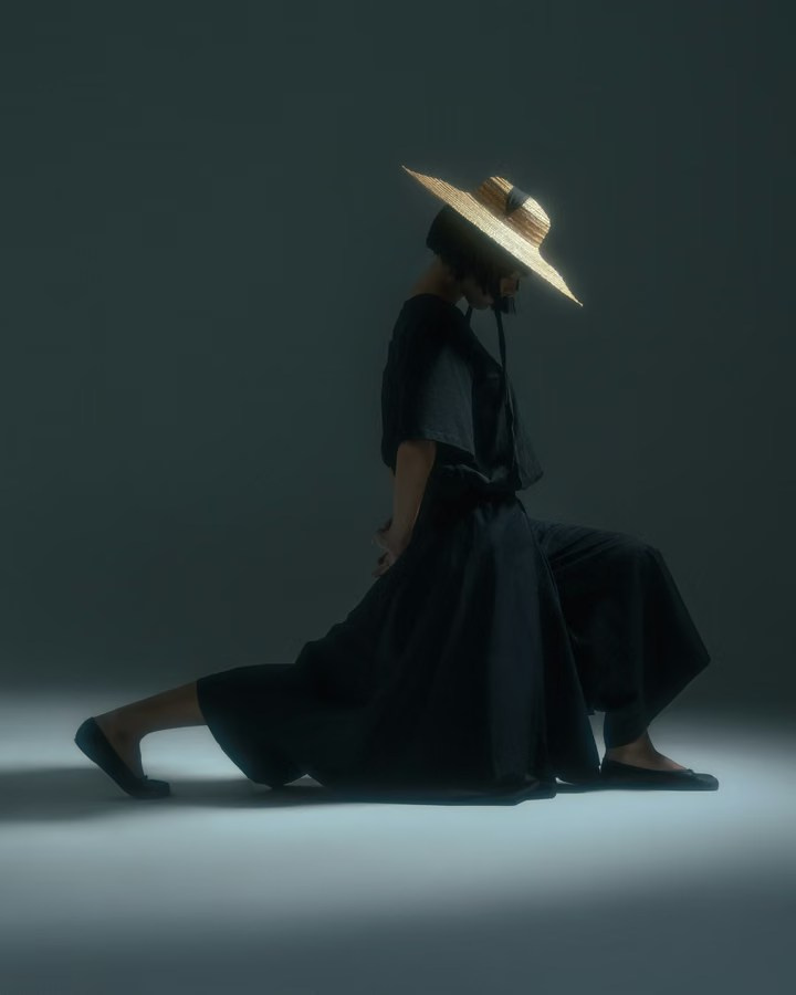 Model wearing a wide-leg black outfit and broad-brimmed hat