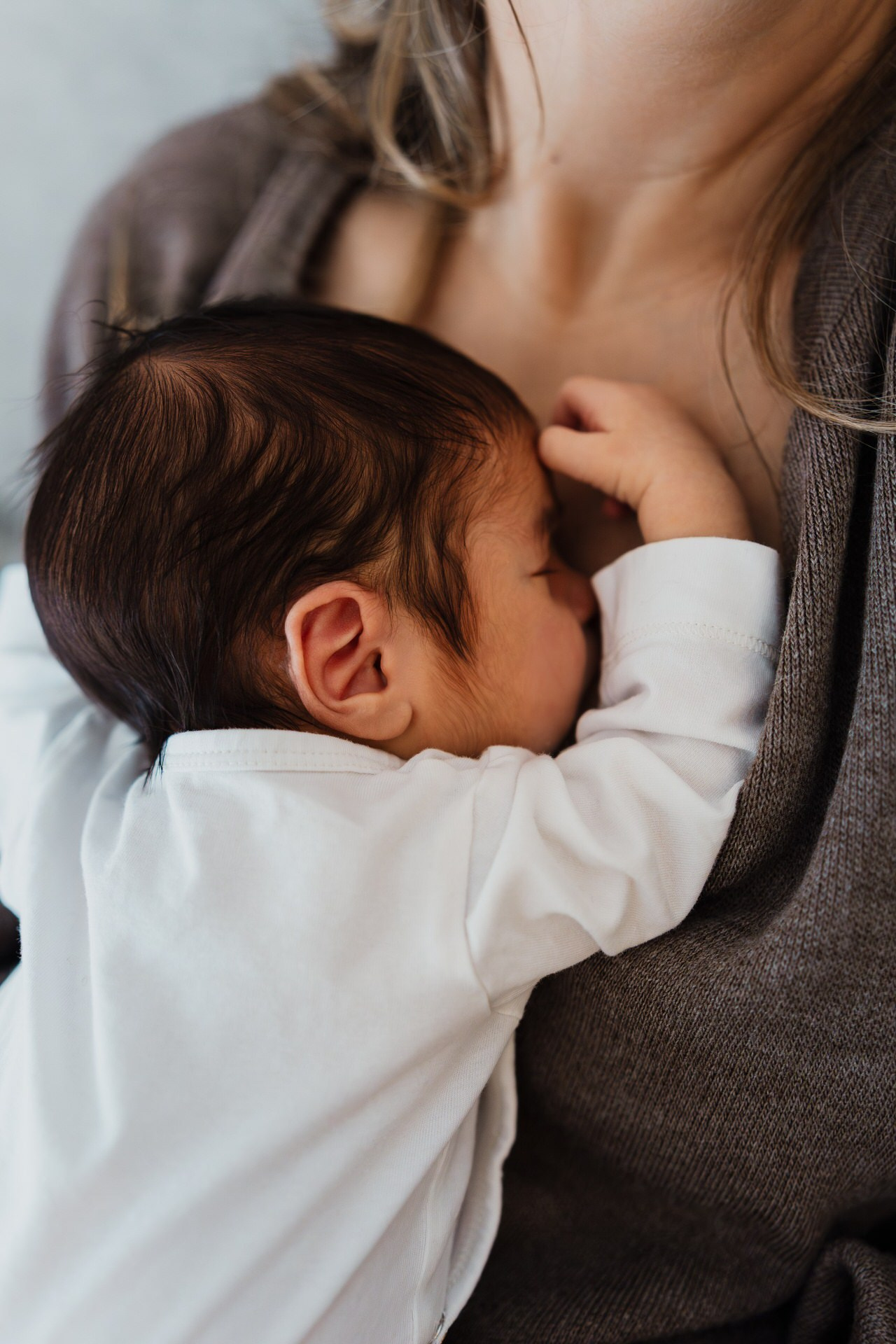 Beba spava u naručju svoje majke. 