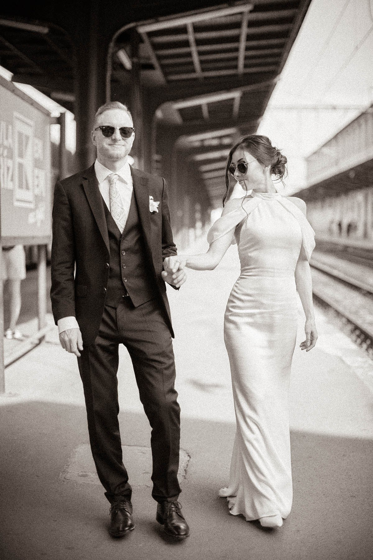 Bride and groom walking along vintage train platforms at Praha-Masarykovo Station, Prague 
