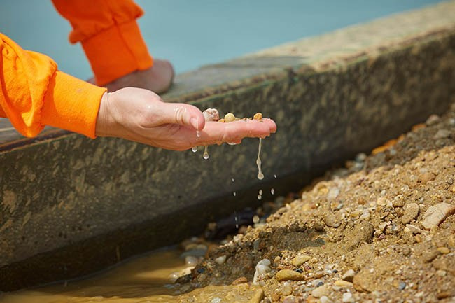 A close-up view of a worker's hand as he checks the dredged stone quality, close-up.