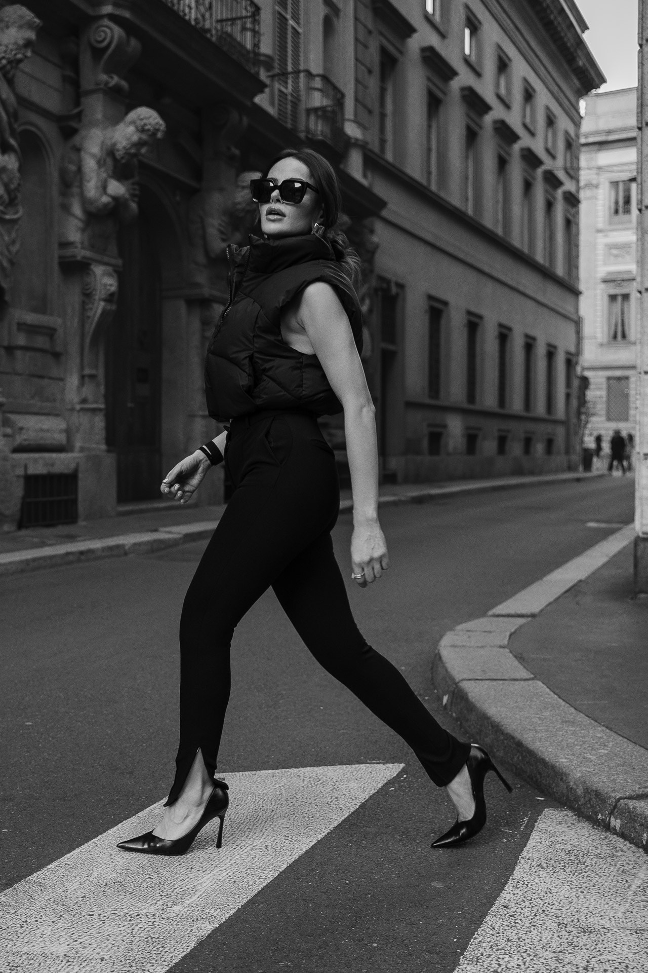 Cinematic black and white street style photography in Milan. Woman walking in fashion outfit, urban portrait session.