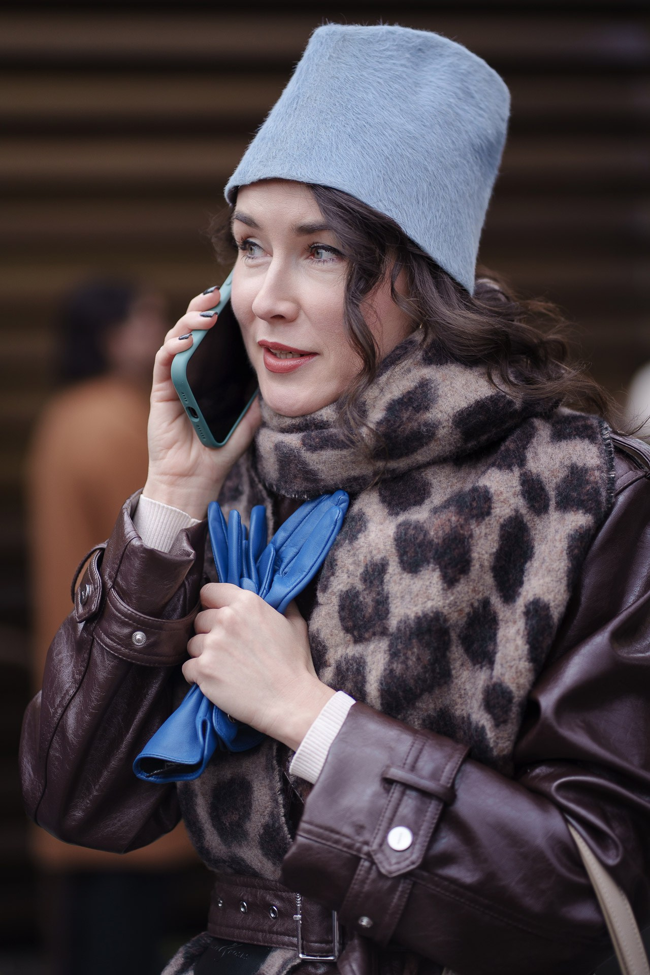 Woman in grey hat and leopard scarf talking on phone at Pitti Uomo Florence