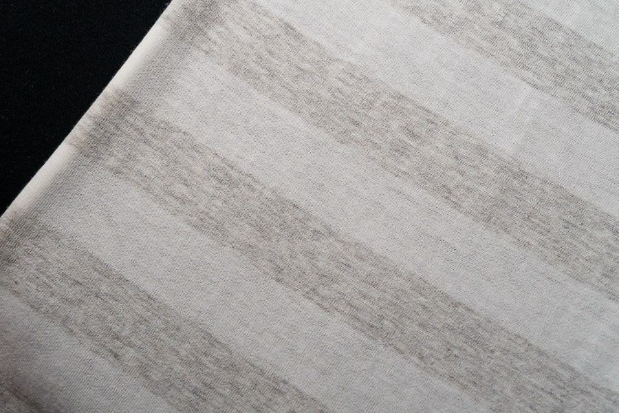 Fotografia têxtil de pormenor em tecido de riscas largas cinzentas e brancas, produzida pela Khave Media