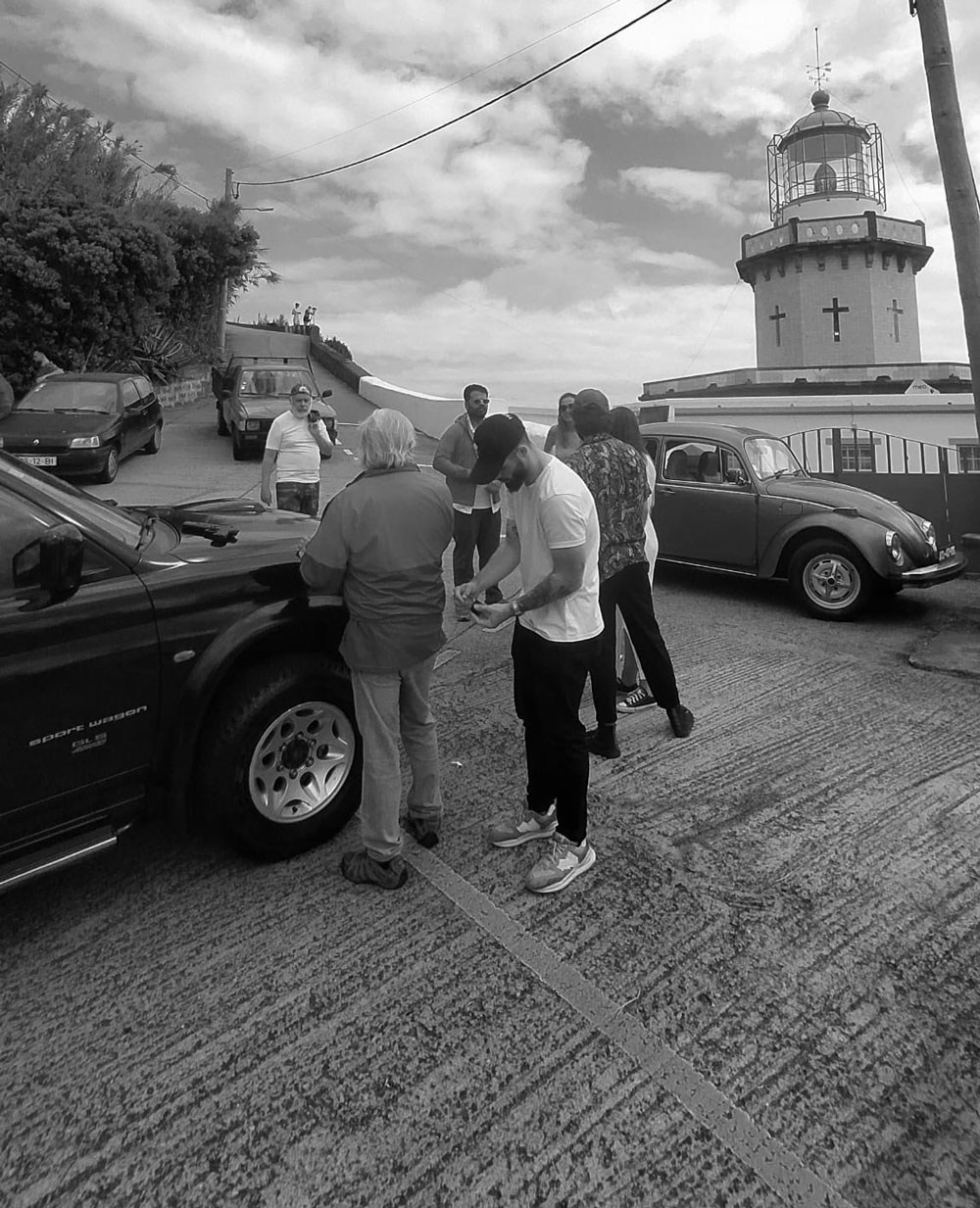 Bastidores de filmagem a preto e branco da equipa da Khave Media junto a um farol costeiro em Portugal