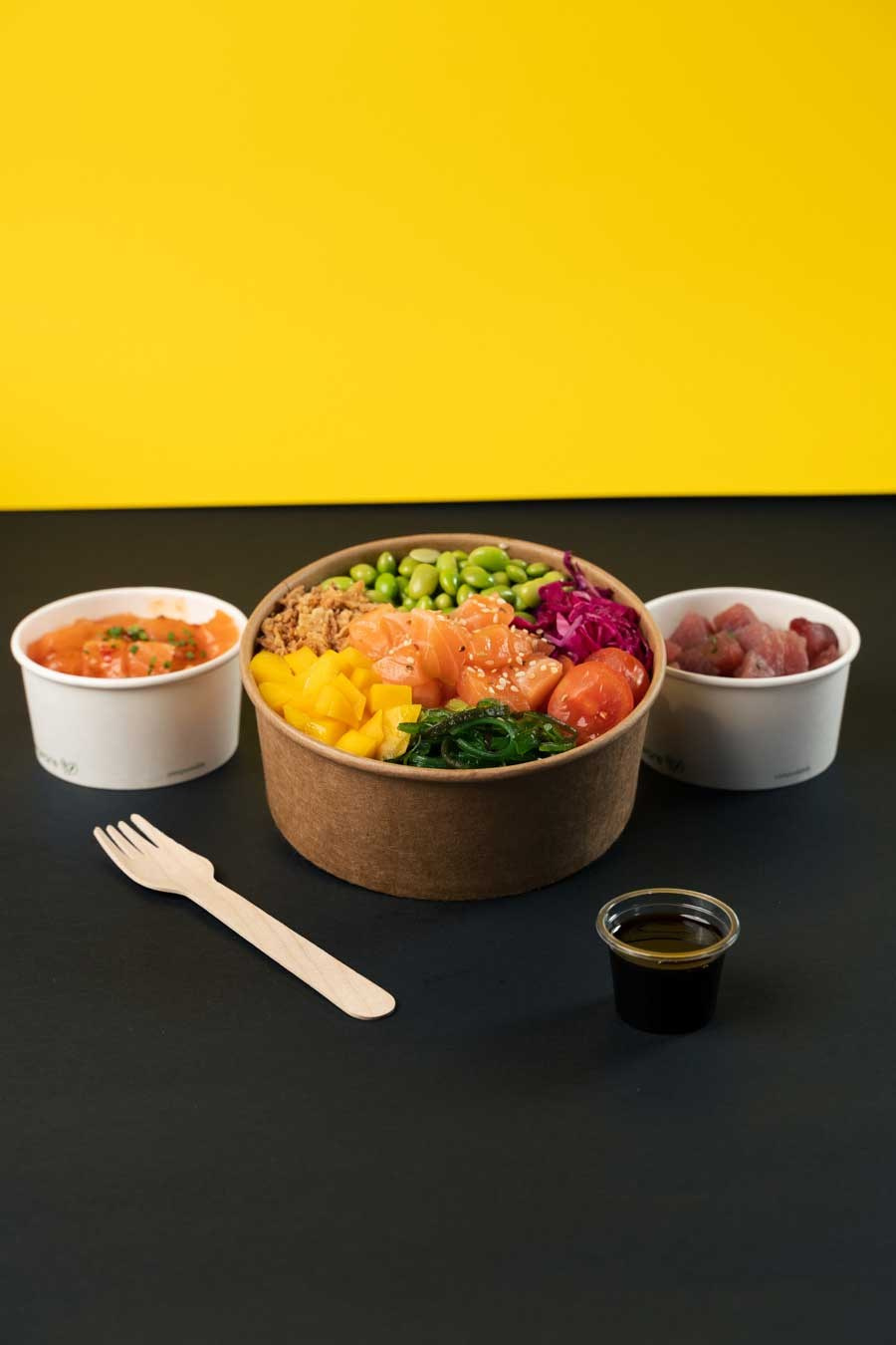 Fotografia criativa de comida em estúdio de uma poke bowl colorida e acompanhamentos com um fundo contrastante amarelo e preto, produzida pela Khave Media