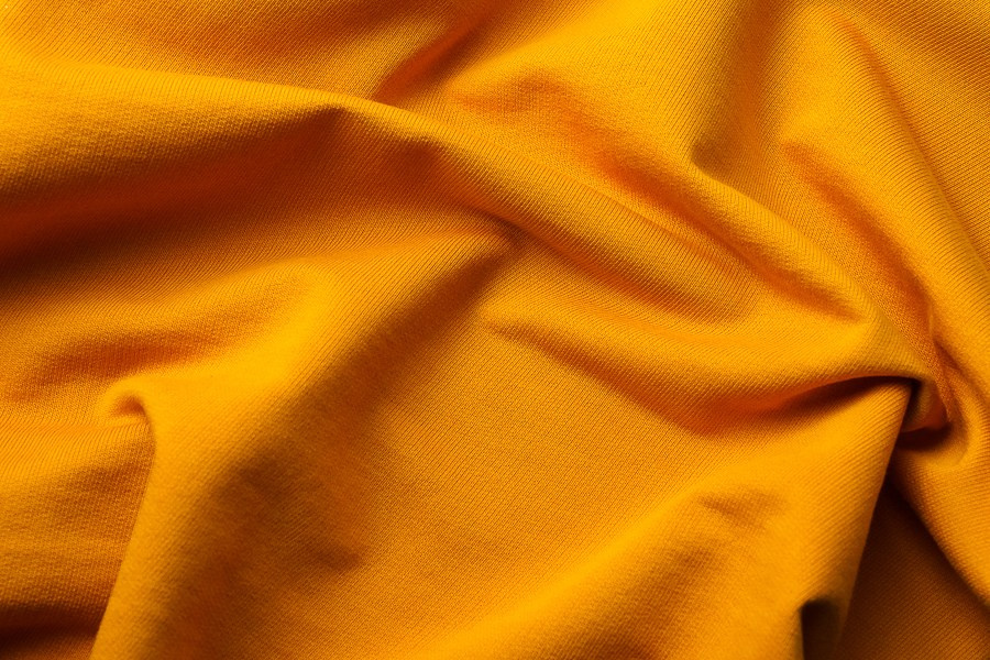 Fotografia comercial de produto com dobras e fluidez num tecido amarelo vibrante, captada pela Khave Media
