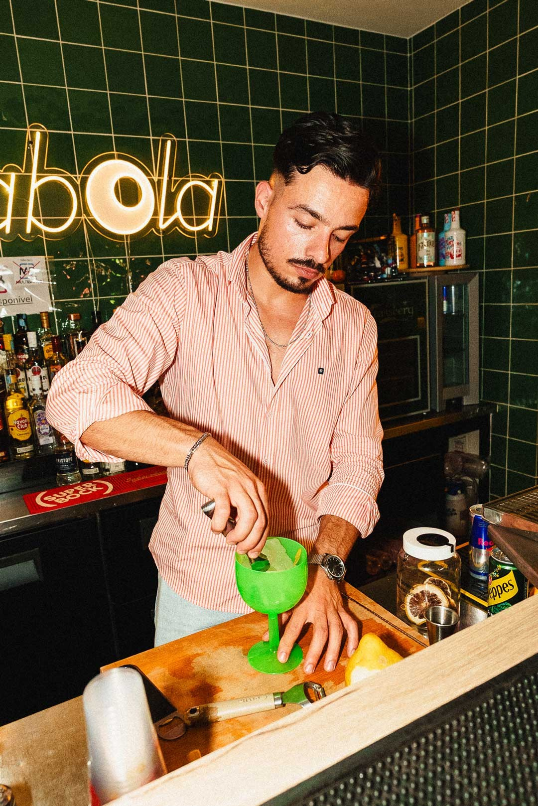 Fotografia de hotelaria e lifestyle de um barman a preparar um cocktail num bar com azulejos verdes ao fundo