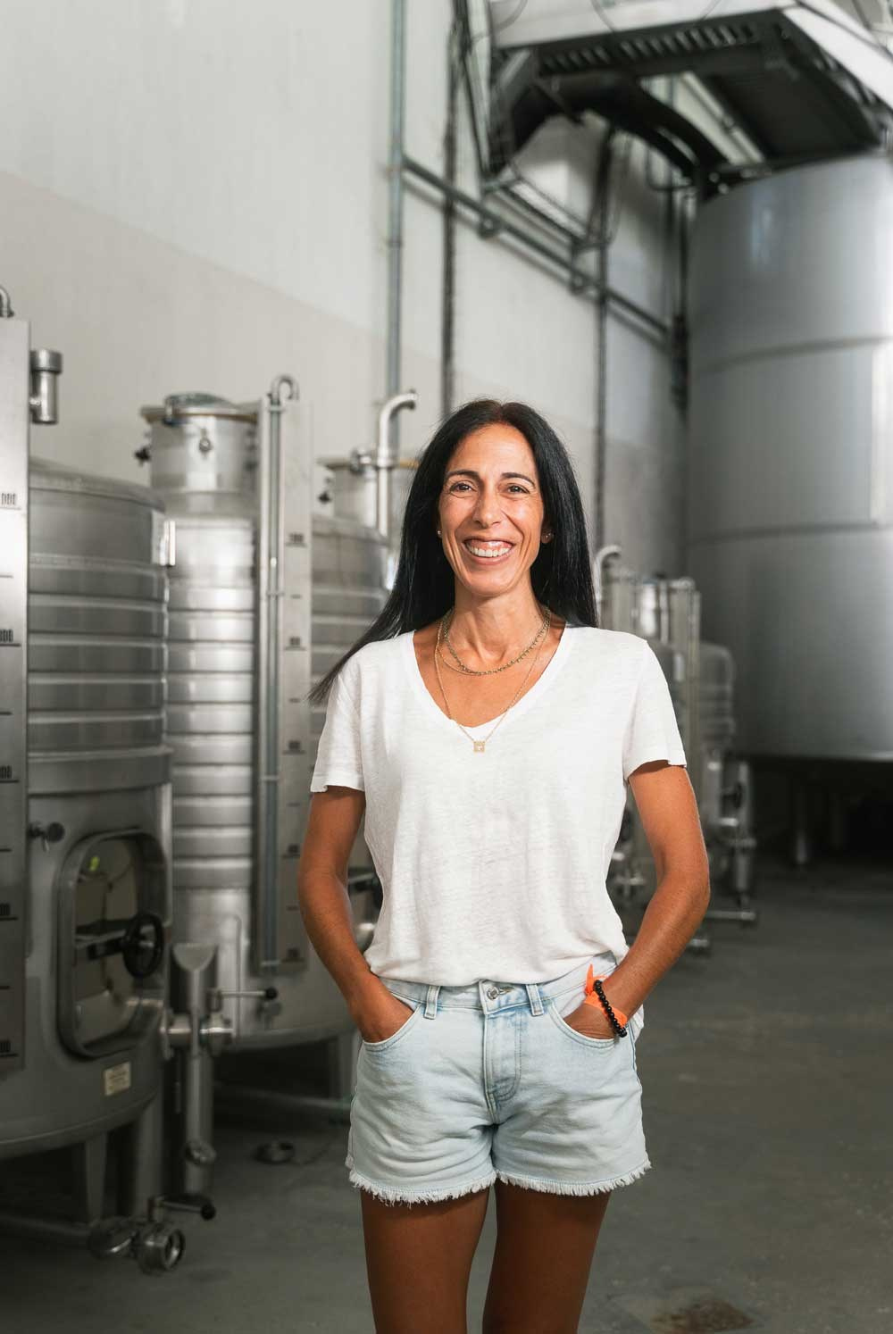 Fotografia corporativa de uma mulher a sorrir num ambiente industrial com grandes cubas de inox, pela produtora Khave Media