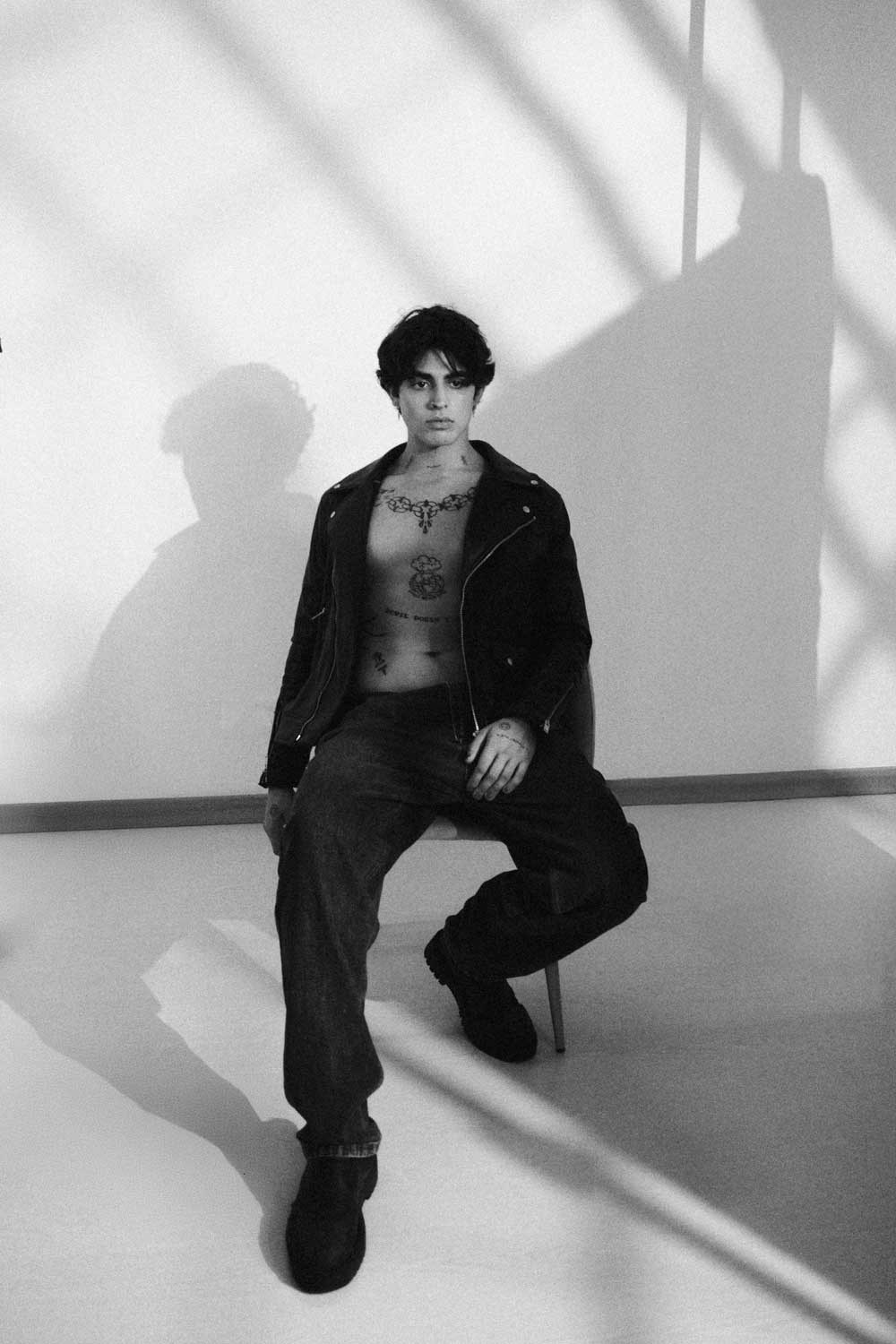 Fotografia de moda a preto e branco de um modelo masculino sentado num estúdio com luz e sombras dramáticas, produzida pela Khave Media