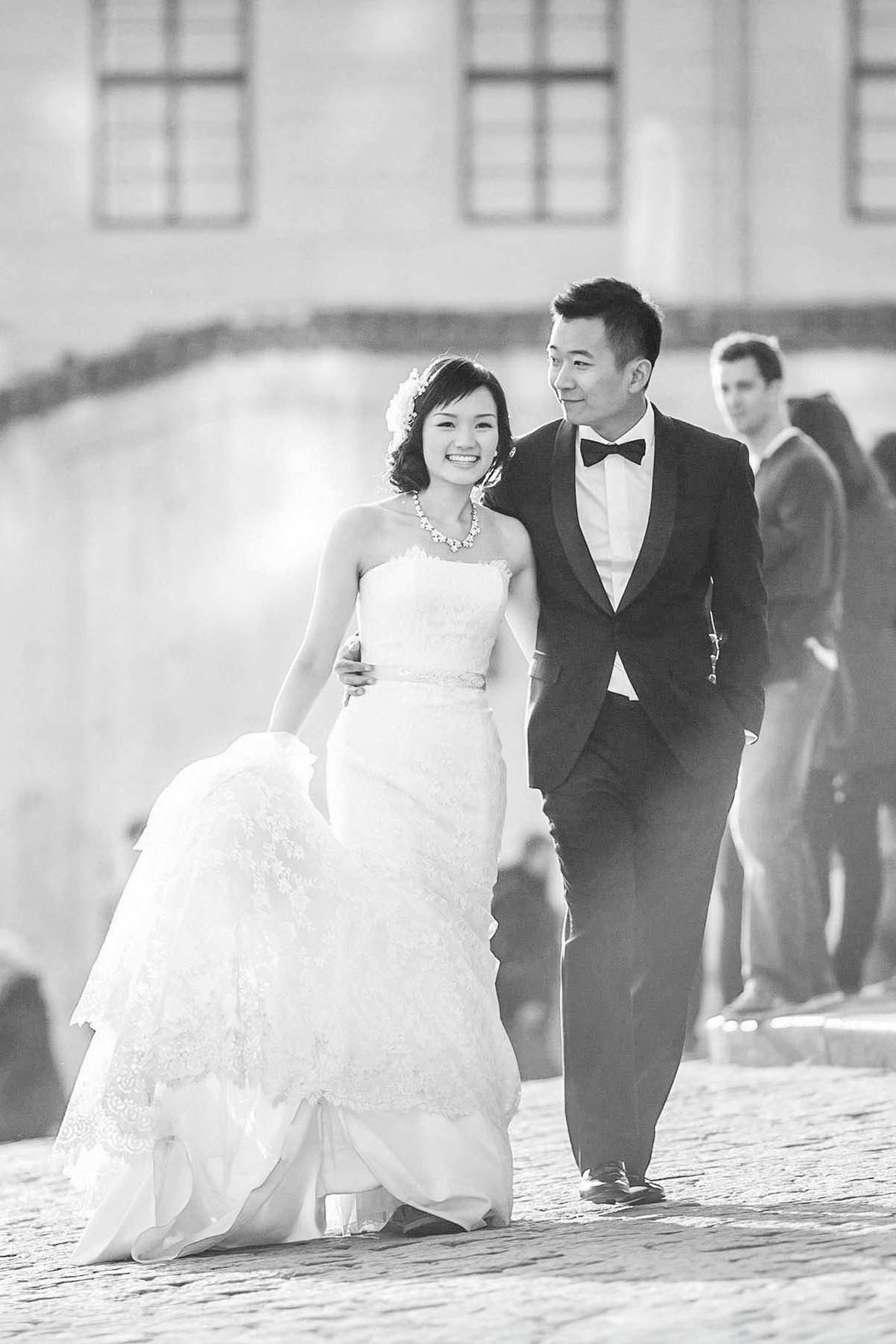 Smiling newlyweds embracing each other as they walk through Prague Castle.