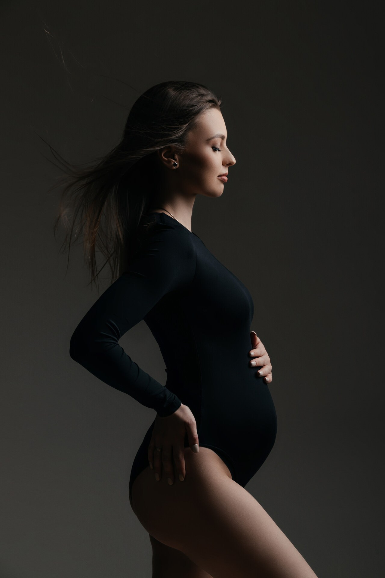 Schwangere Frau im Studio mit dunklem Hintergrund