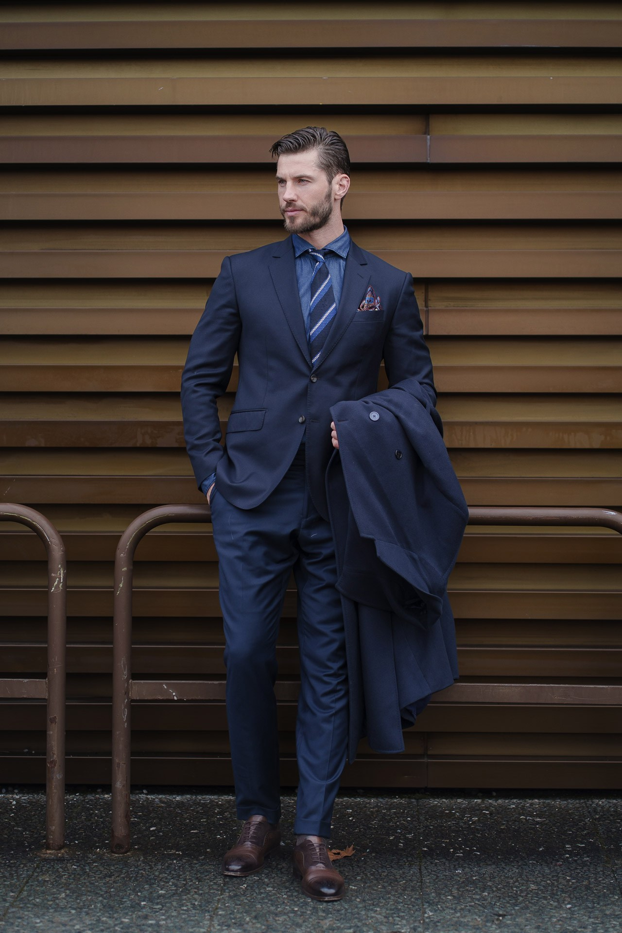 Man in blue suit posing against wooden wall at Pitti Uomo Florence