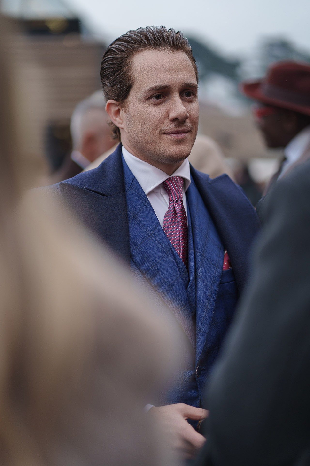 Man in blue suit and red tie talking during Pitti Uomo 109 Florence