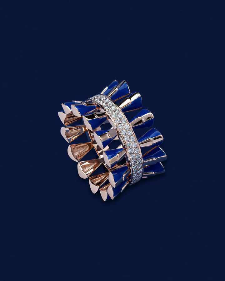 Gold ring with blue enamel inlays and a diamond band on a dark blue background