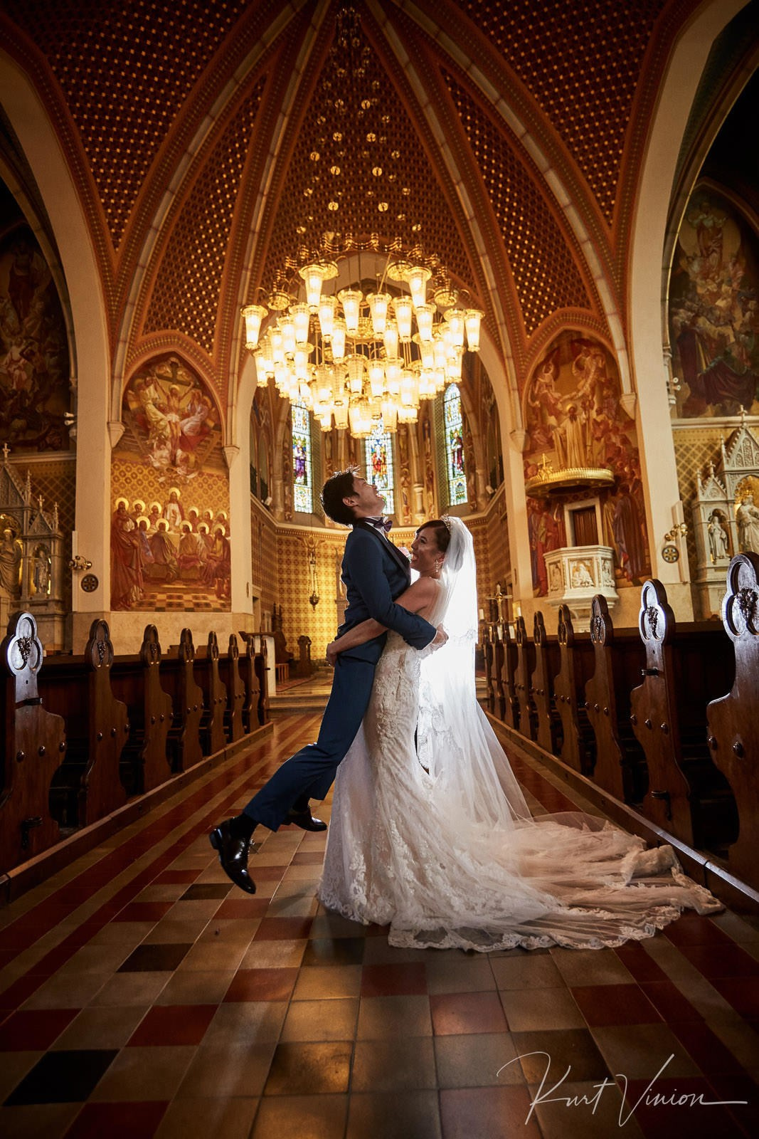 Bride playfully lifting astonished groom inside church portrait.
