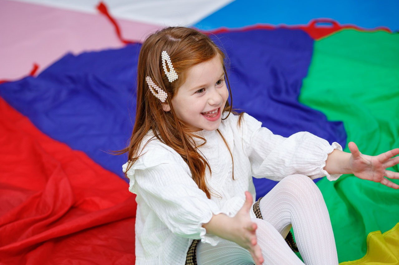 Devojčica uživa u igri na mekanim šarenim podlogama.