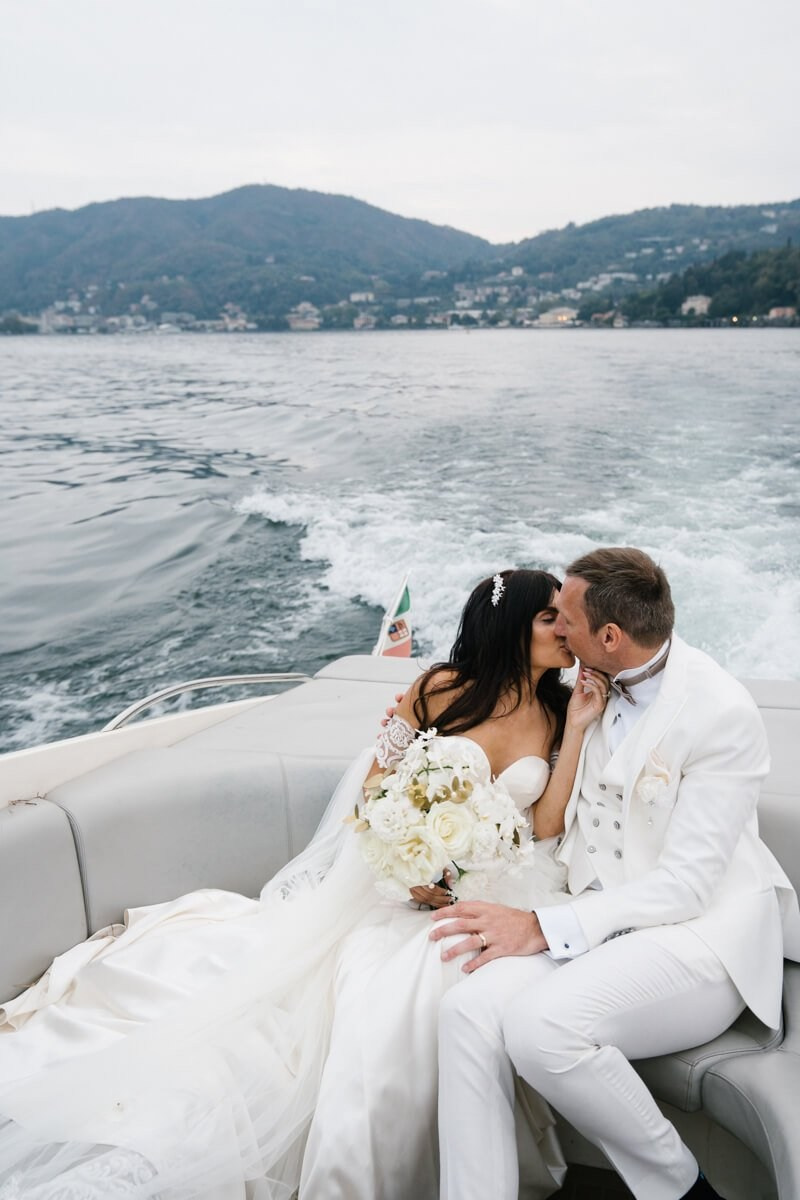 Bride and groom kissing on boat on Lake Como
