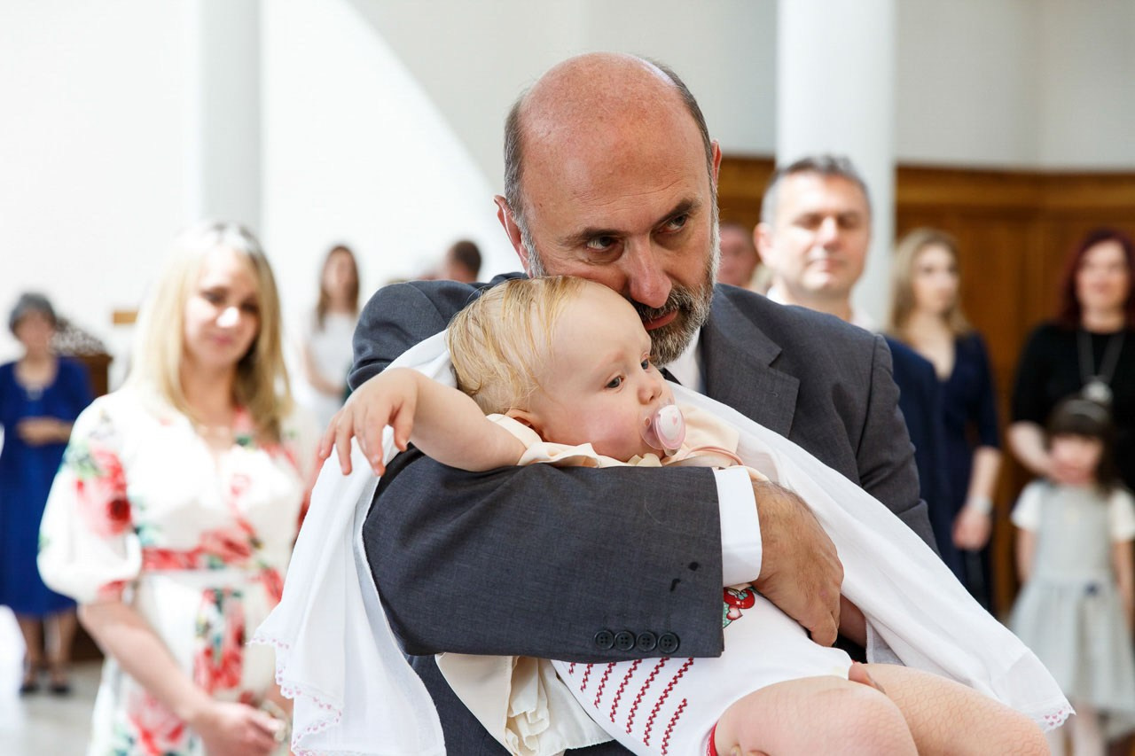 Kum drži bebu u naručju tokom ceremonije krštenja.
