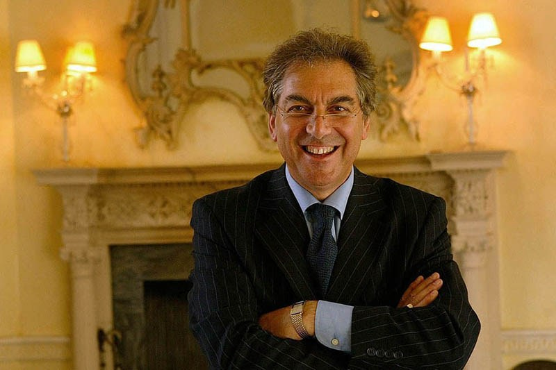 Senior executive headshot captured on location near a fireplace in a historic manor house.