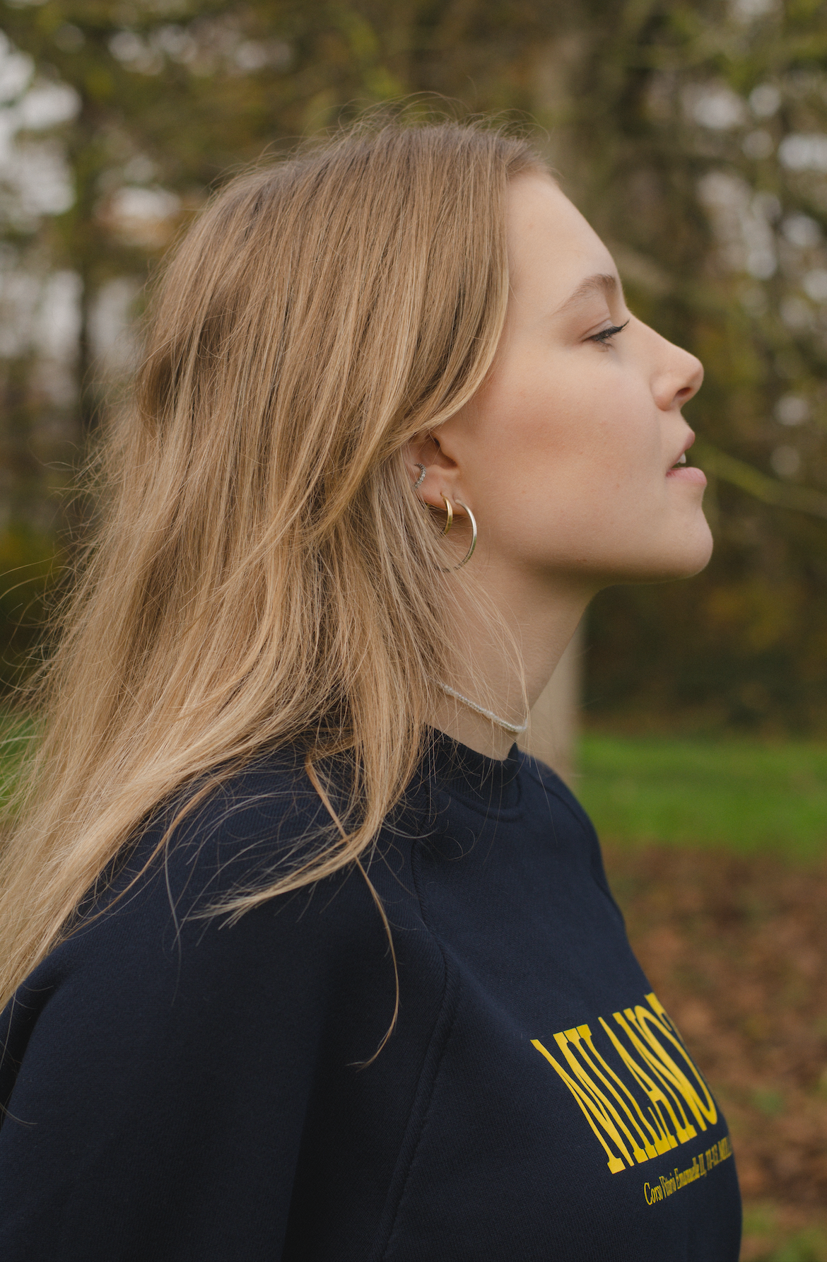 Seitenprofil Porträt einer jungen Frau mit blonden Haaren vor einem Naturhintergrund
