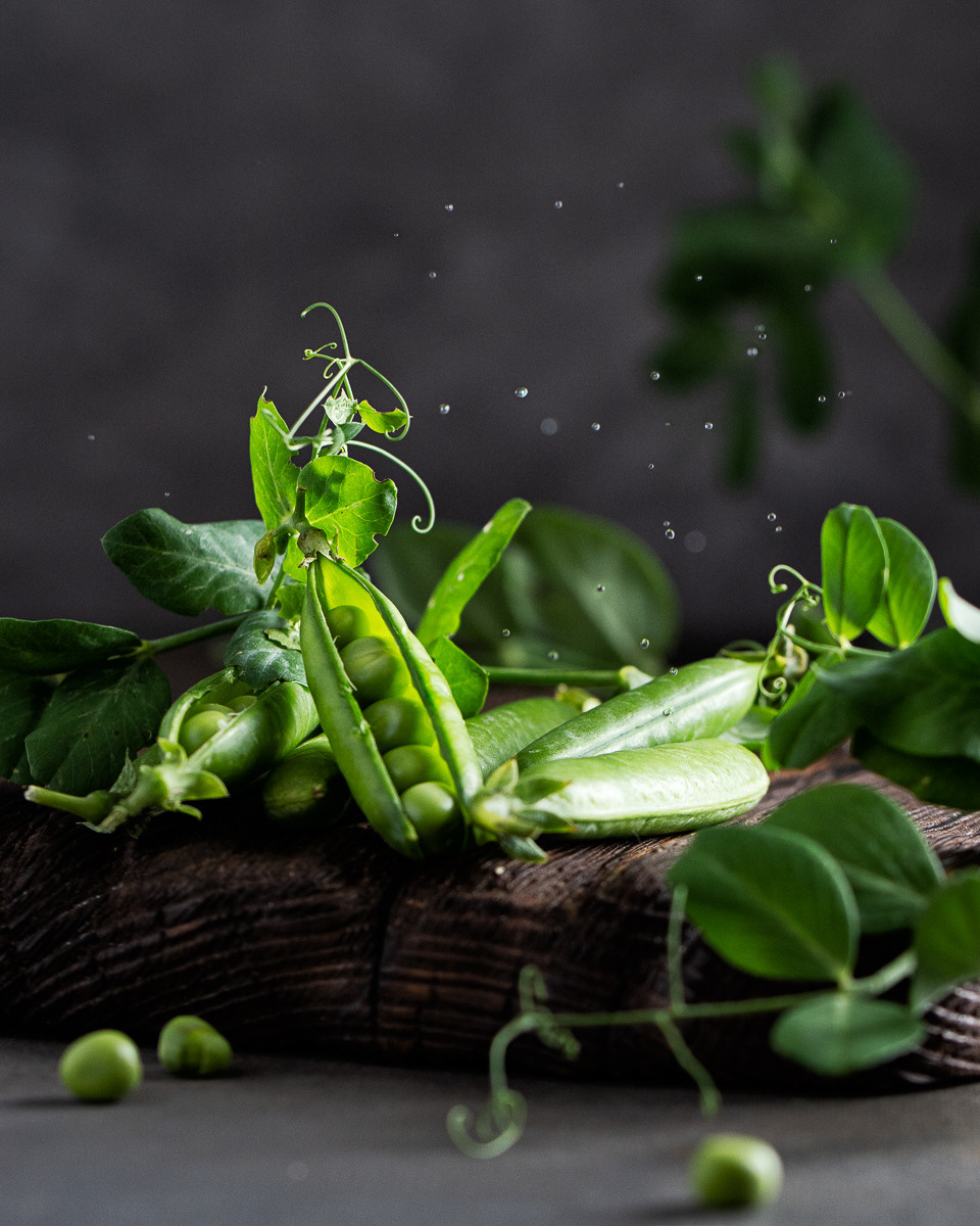 Ganze Grüne Erbsen mit Wassertropfen auf dem Holzbrett
