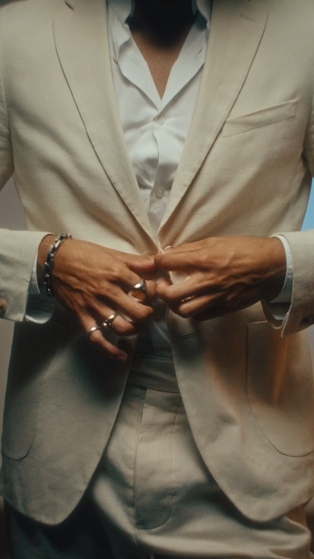Close-up of a male model adjusting his beige suit, emphasizing modern menswear for a luxury fashion campaign.