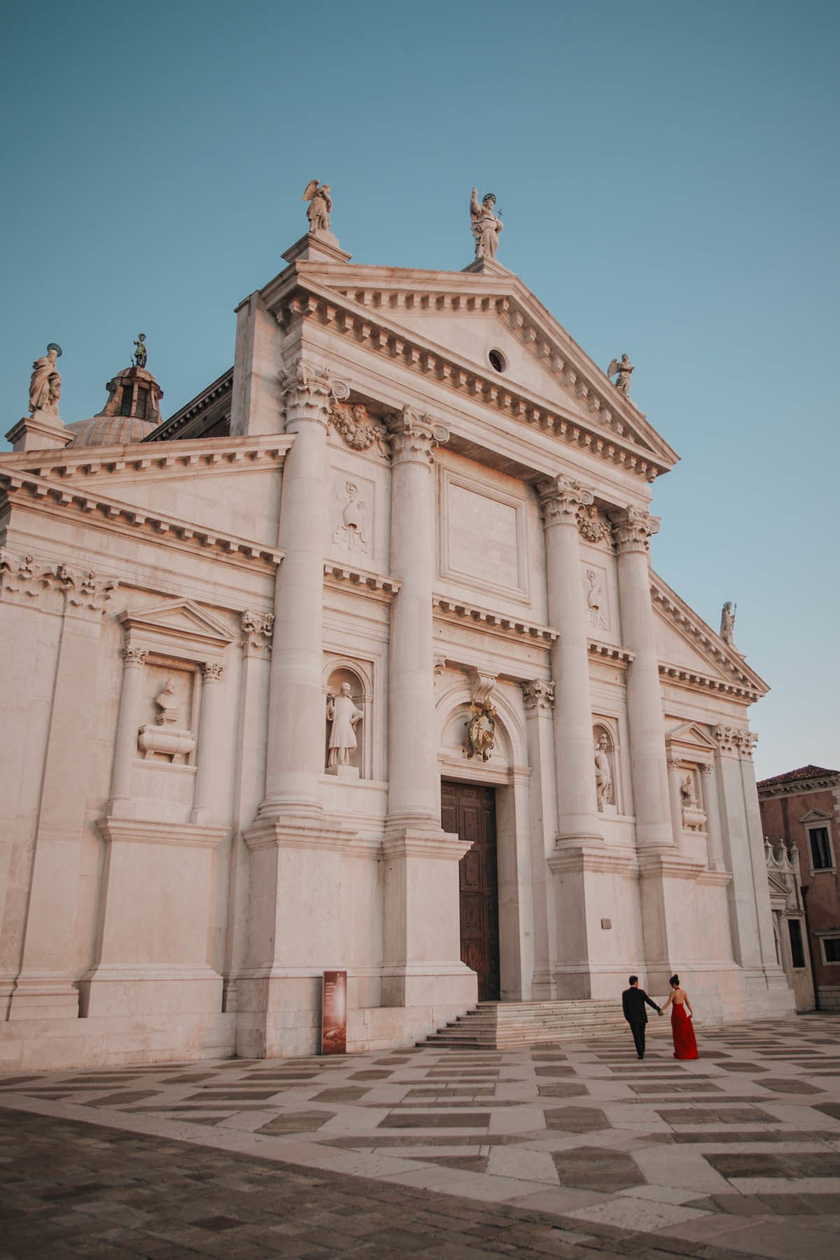 Young Asian couple walking across the plaza at San Giorgio Maggiore island in Venice at sunset.