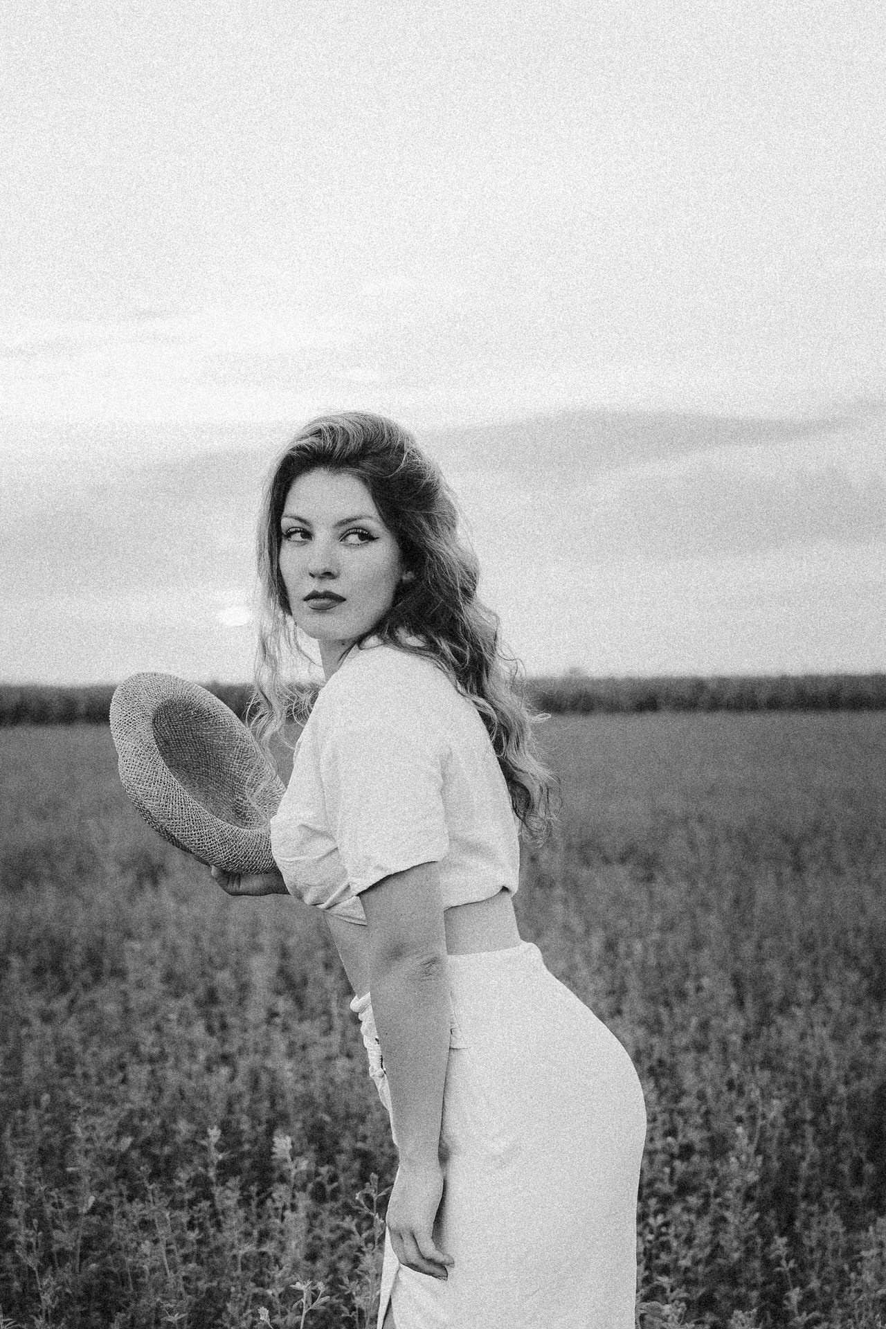 crno bela fotografija devojke koja stoji na poljani prilikom stvaranja autentičnog portreta