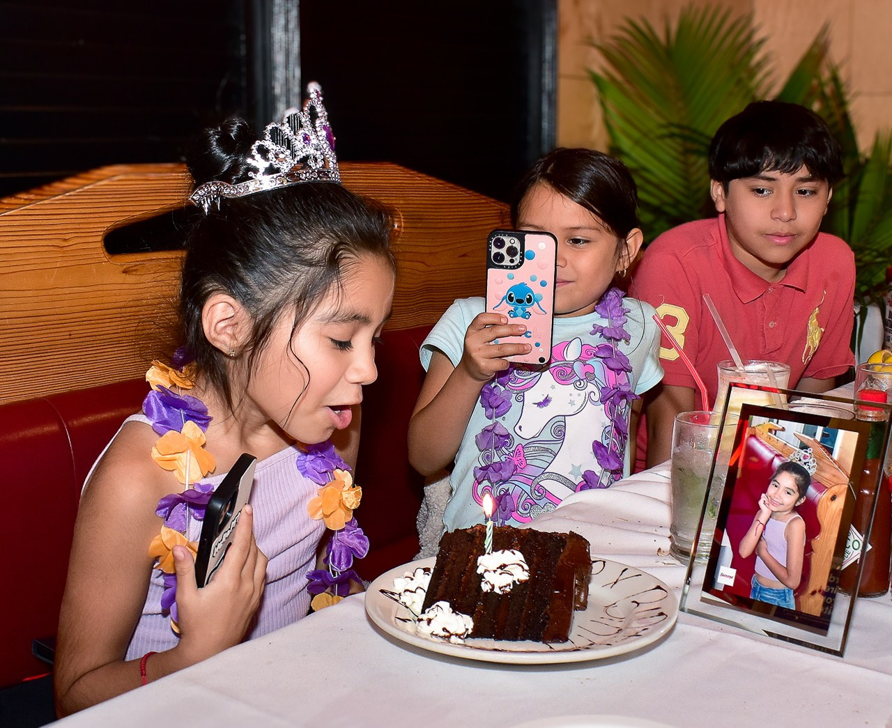 Birthday girl blowing candles on a cake at a restaurant table, kids birthday celebration photography.
