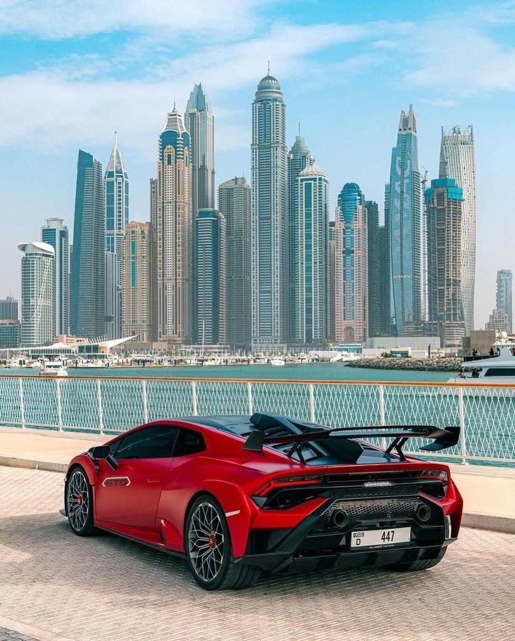 A red Lamborghini on a palm tree in Dubai against the backdrop of skyscrapers. There is a Dubai marina on a red Lamborghini van. 