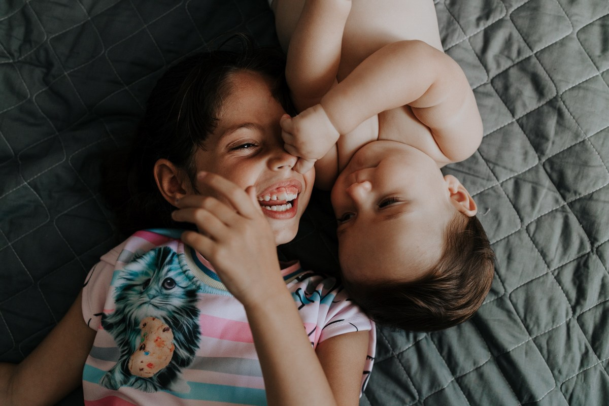 Irmãos brincando e sorrindo deitados juntos