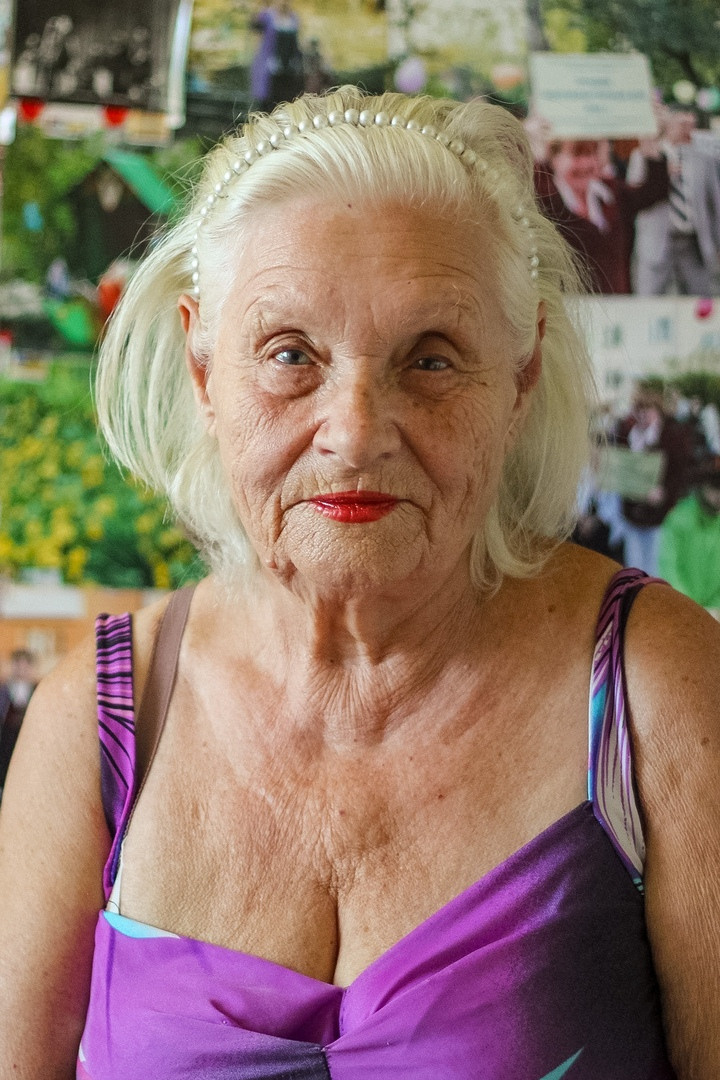 Бабушка, посвятившая жизнь выращиванию цветов и высадке деревьев во дворе многоэтажного дома.