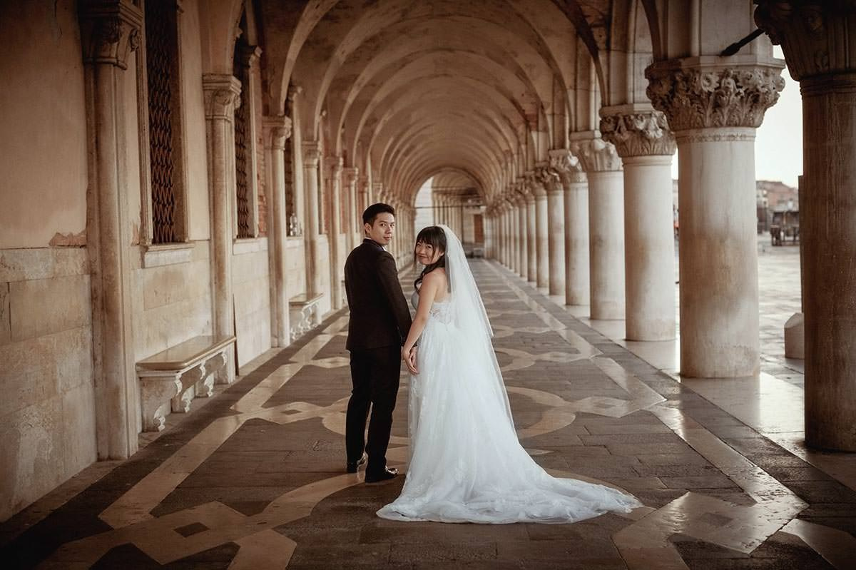 Couple walking near the historic Doge's Palace at dawn during pre-sunrise honeymoon shoot