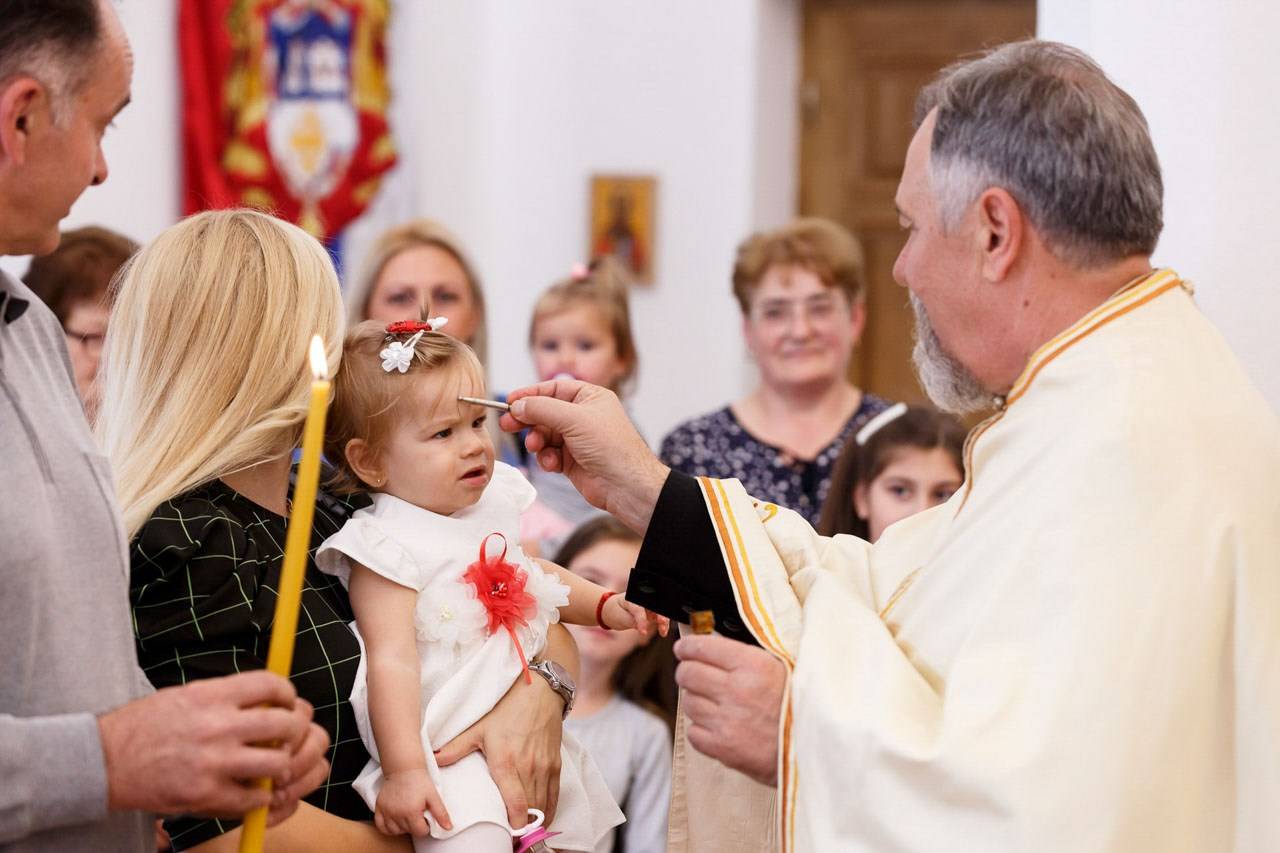 Sveštenik drži bebu tokom tradicionalnog obreda krštenja.