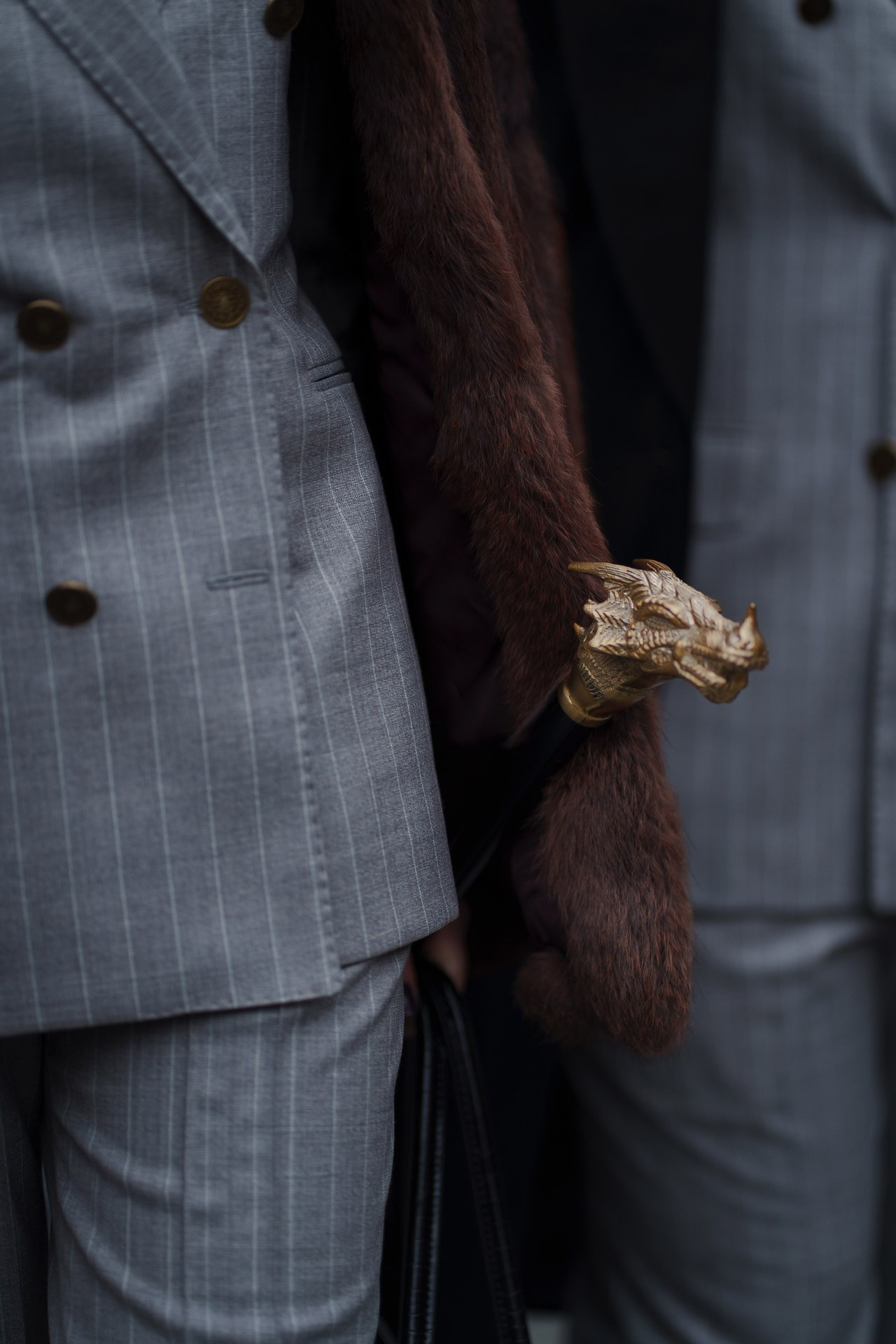 Detail of grey suit with fur scarf and gold animal handle cane at Pitti Uomo