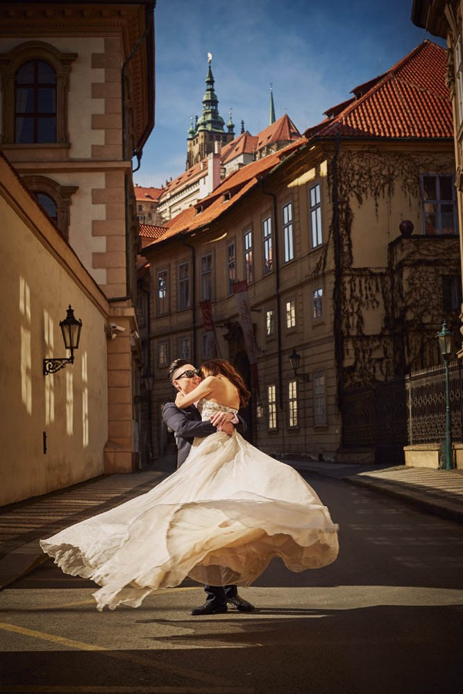 A man picks up his bride and spins her around in the heart of Mala Strana as St. Vitus Cathedral looms above.