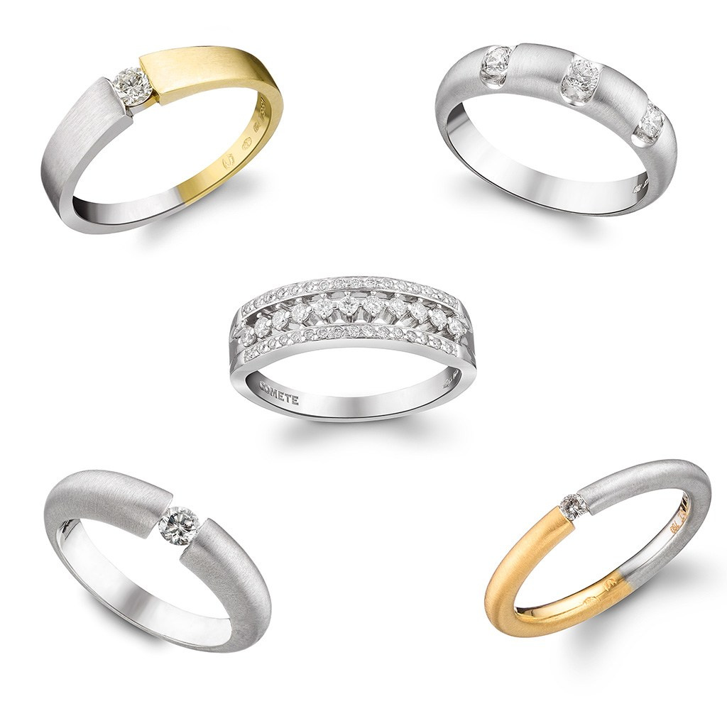 Pet zlatnih dijamantskih prstena na beloj pozadini.