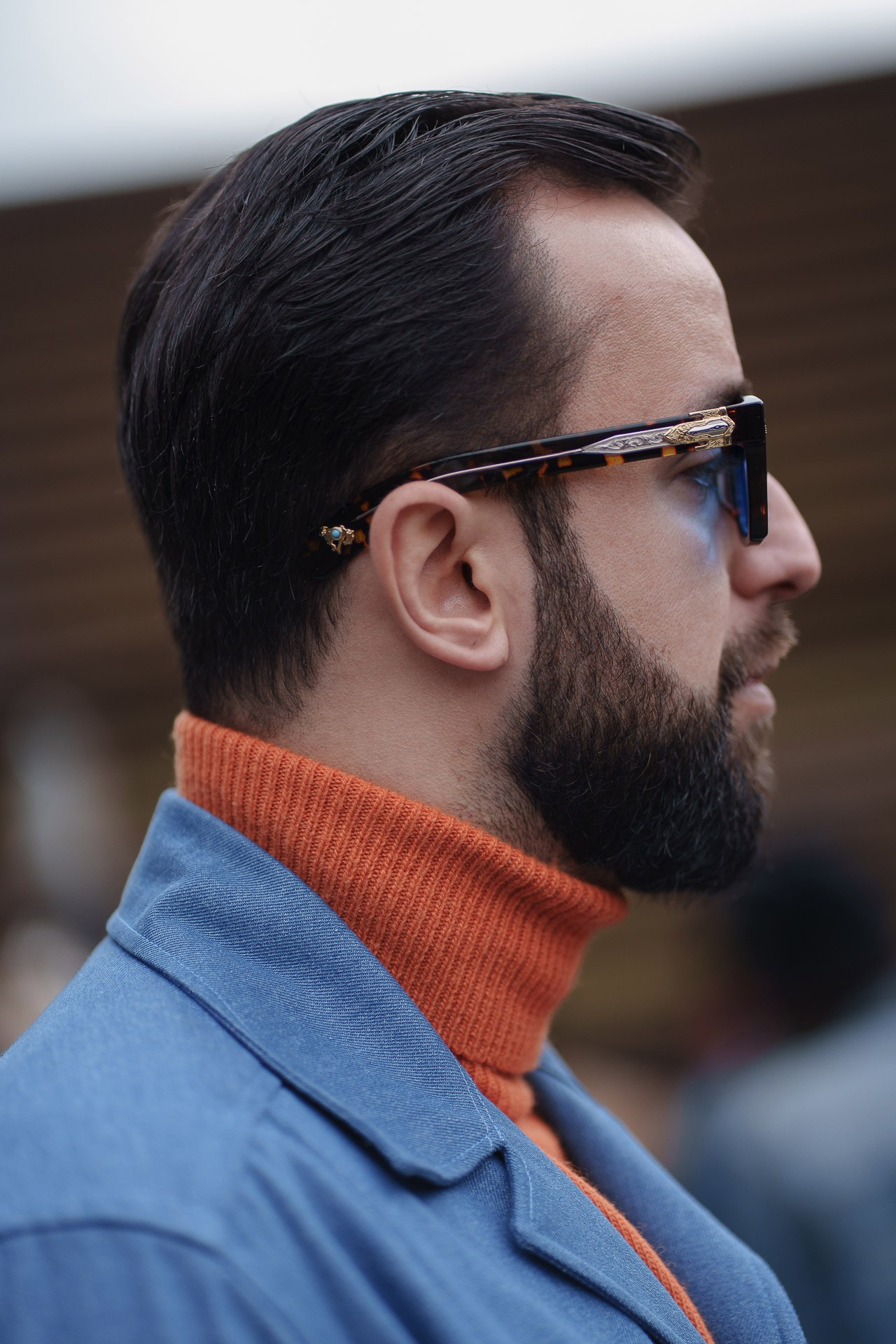 Man in blue coat with orange turtleneck and sunglasses at Pitti Uomo Florence