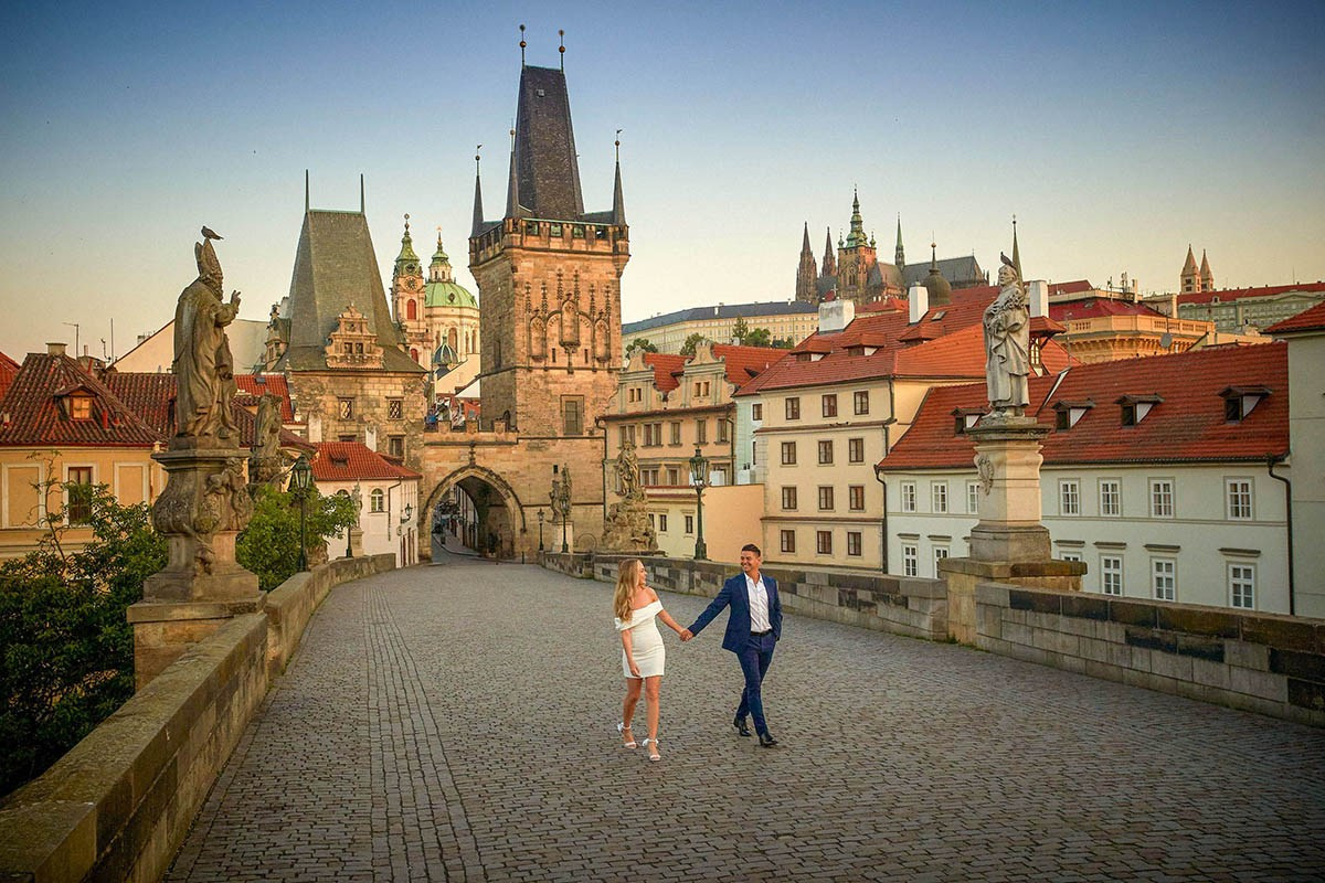 Man blue suit, blonde woman, Charles Bridge, sunrise, Prague