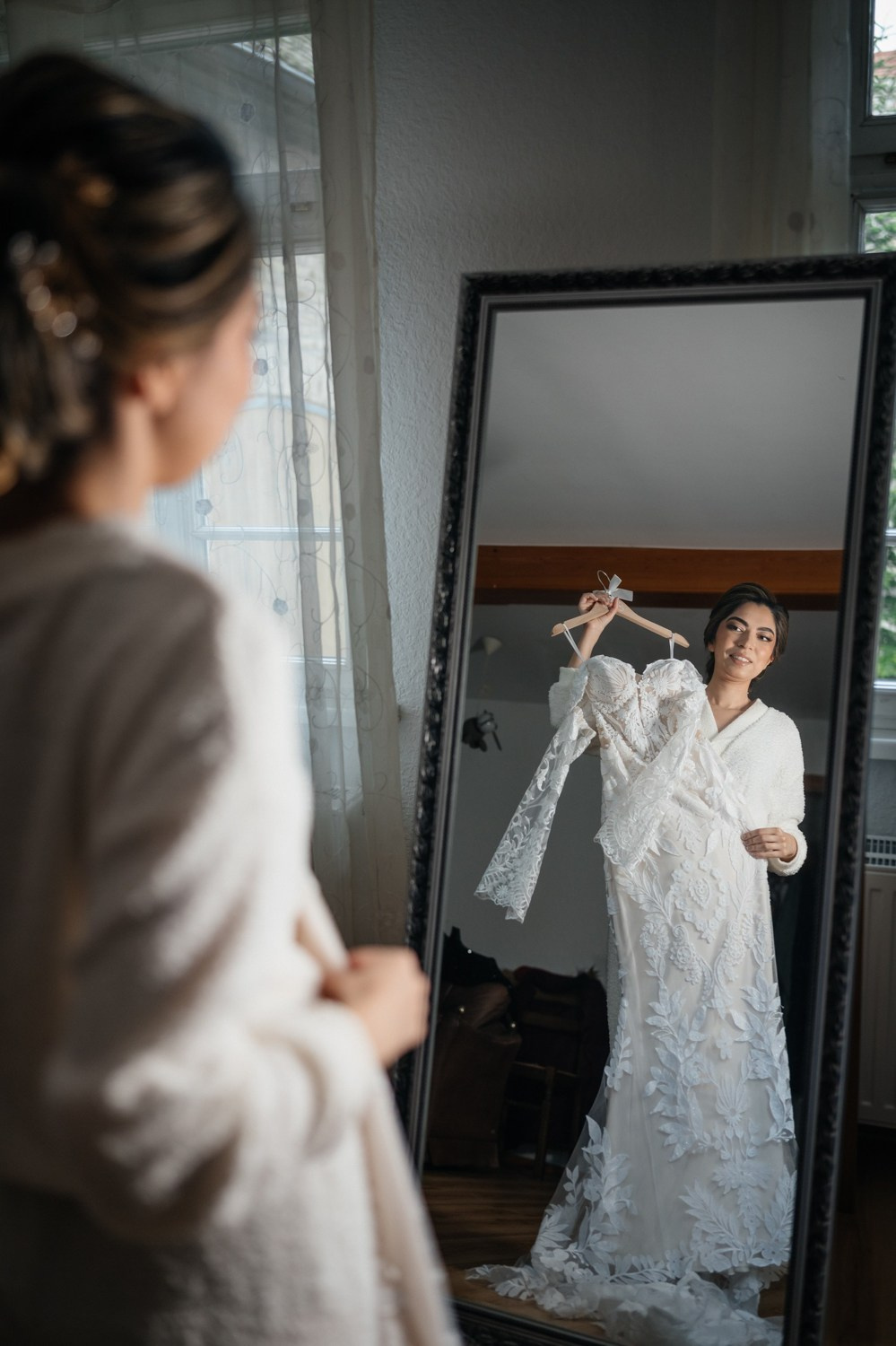 bride holding dress in front of mirror