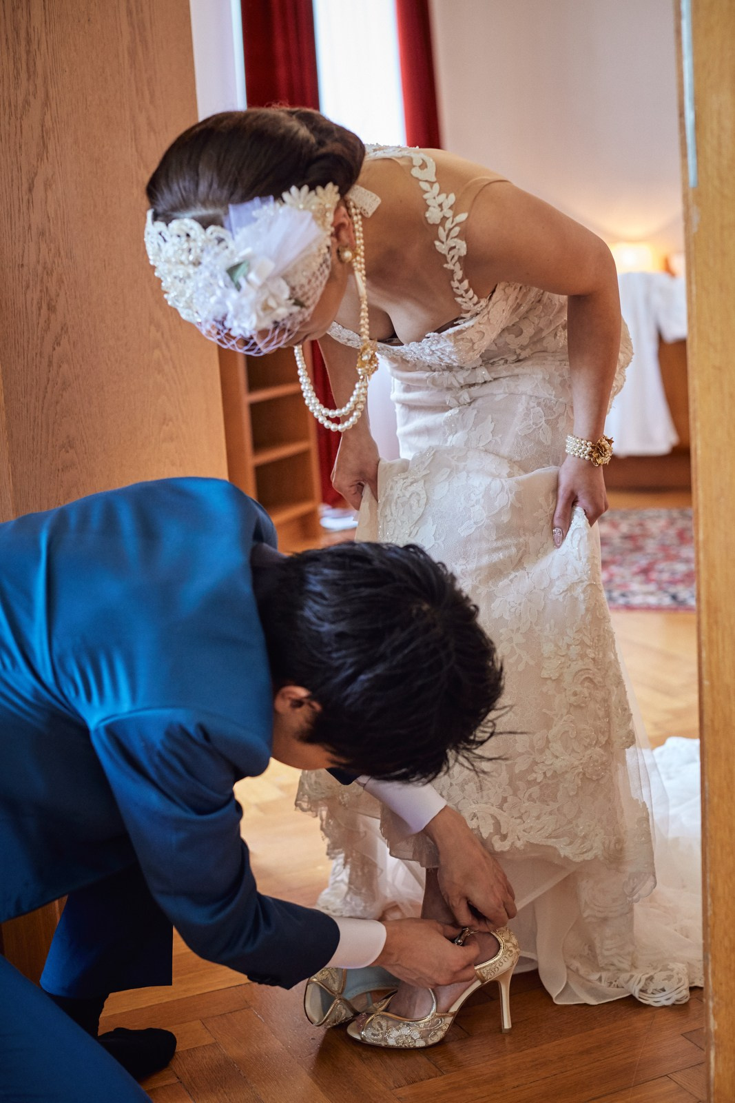 Groom assisting bride with shoes in luxury Vila Bled suite.