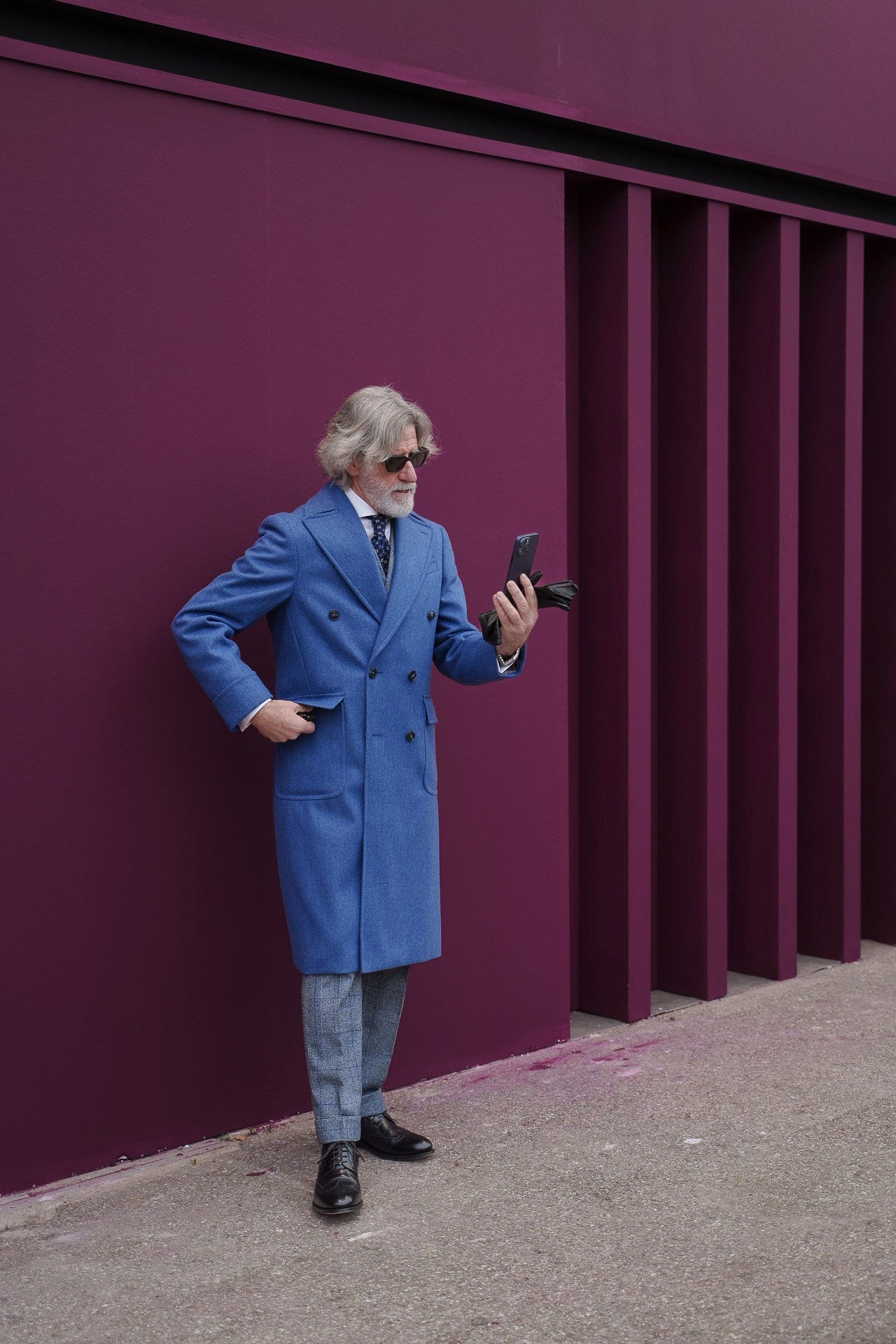 Man in blue coat checking phone during Pitti Uomo 109 Florence