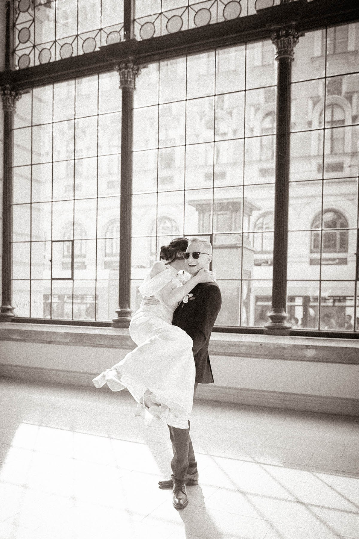 Bride and groom spinning and laughing together in warm sepia tone at Praha-Masarykovo Station