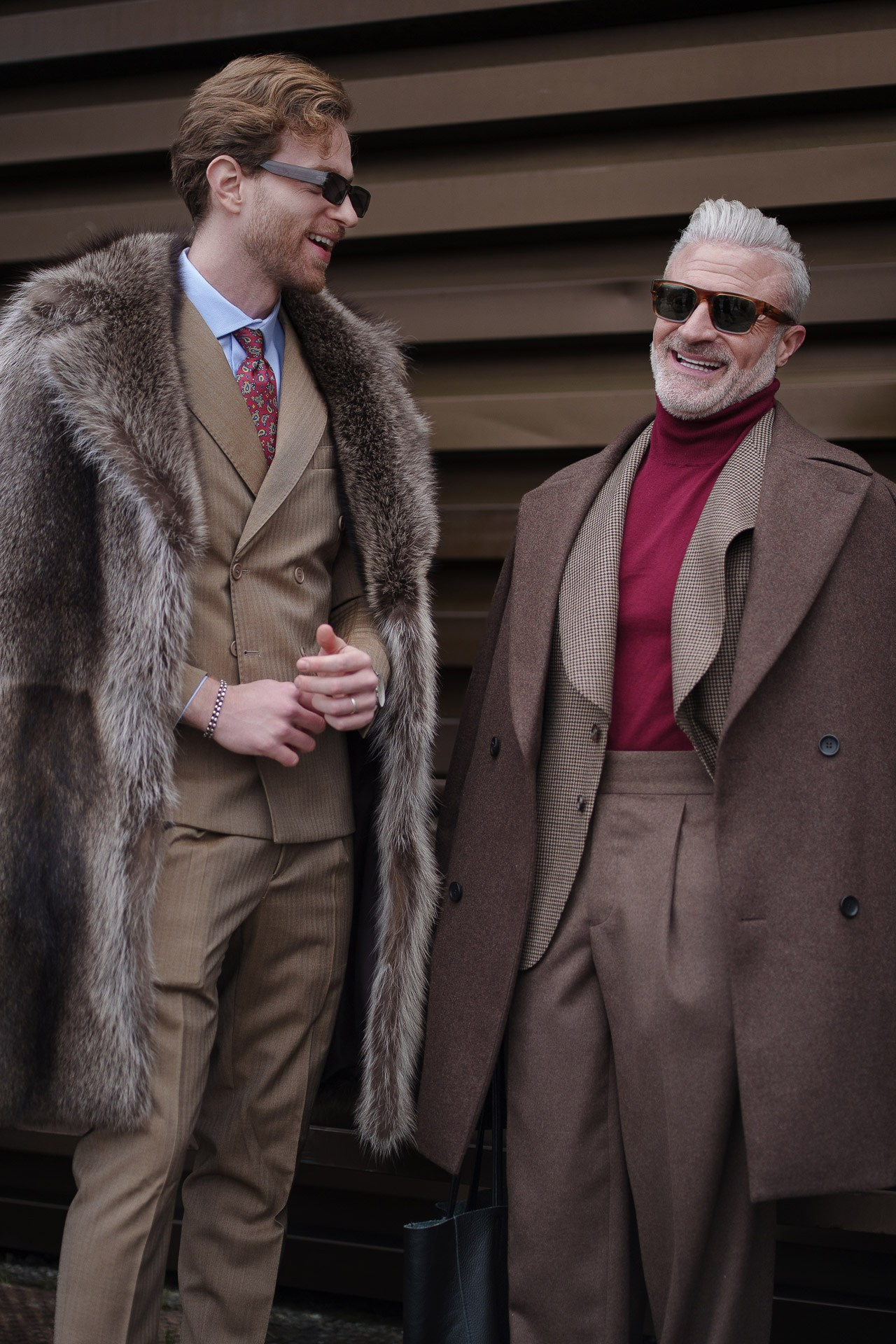 Two stylish men wearing fur coats and suits at Pitti Uomo 109 Florence