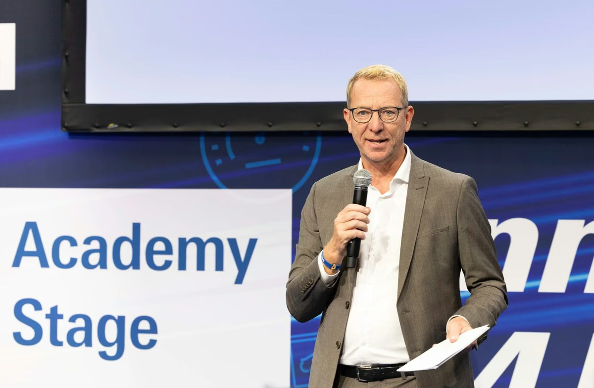 Senior speaker presenting on the Academy Stage at a trade exhibition