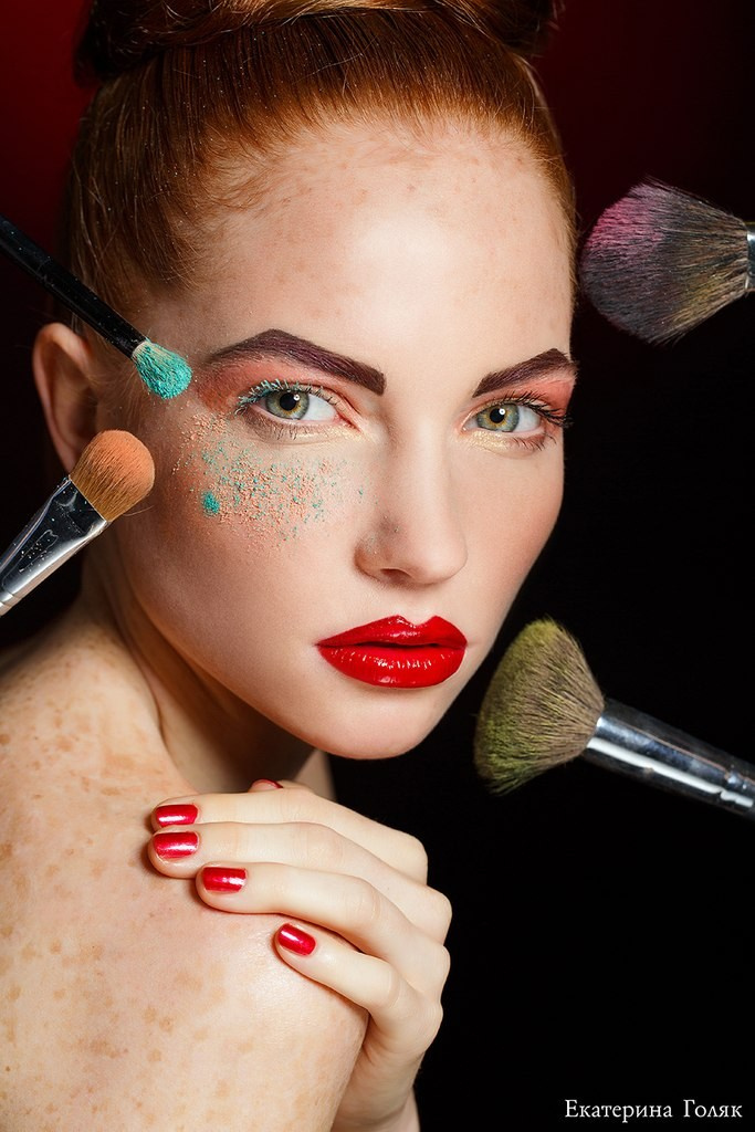 Model with red lipstick, exuding confidence and allure. Her makeup is dramatic, highlighting her eyes and lips, while her hair is styled to complement her bold look. The background is understated, allowing her striking features and vibrant lipstick to stand out. This image captures the essence of classic beauty with a modern twist.