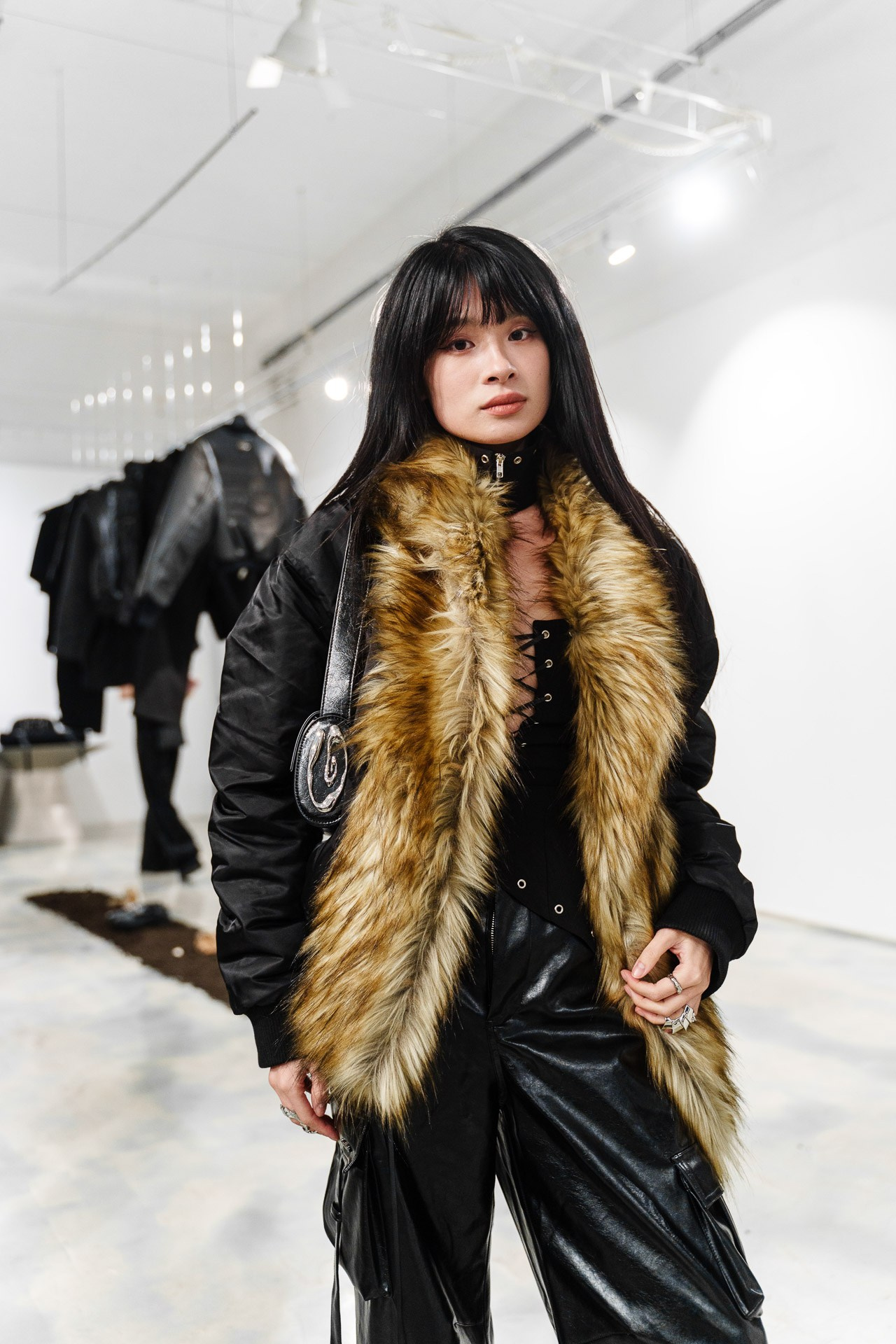 Trendy fashion portrait of a woman wearing a black outfit with a faux fur collar at a fashion event in Milan.